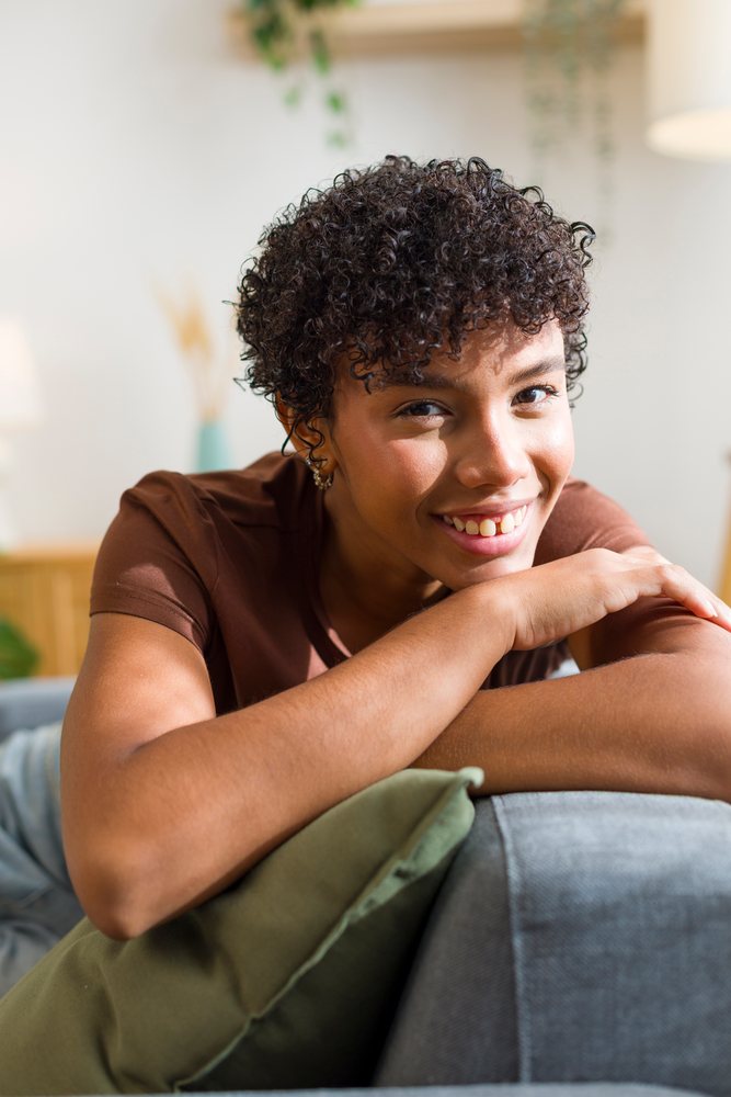 Young African American woman smiling and relaxing on sofa at home