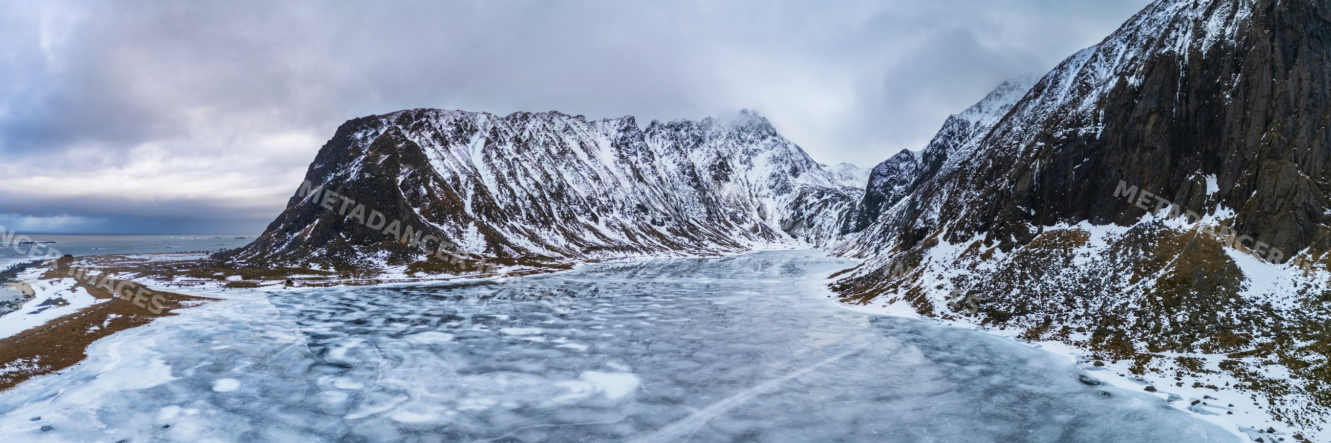 Frozen lake with snowy mountains at eggum nature reserve in Lofoten
