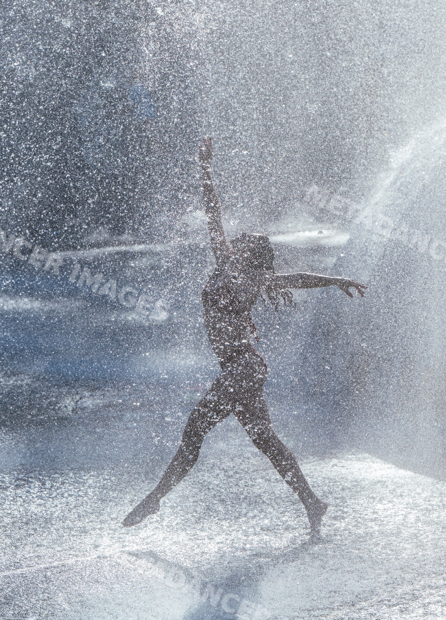 White woman jumping dynamically in water spray outdoors