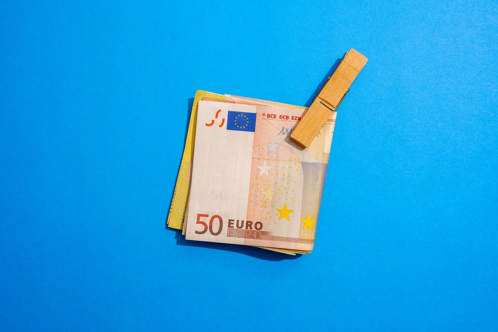 Euro notes clipped with wooden clip on blue background