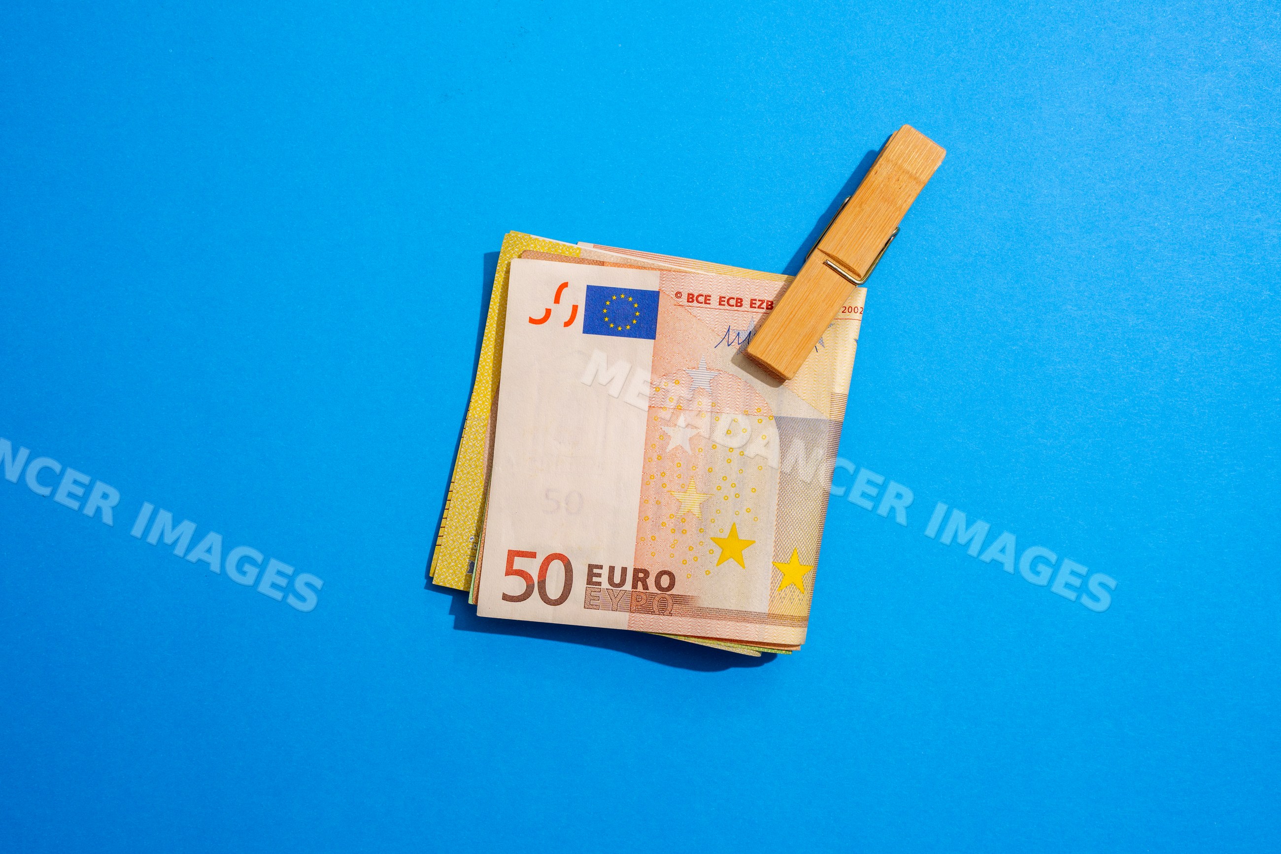 Euro notes clipped with wooden clip on blue background