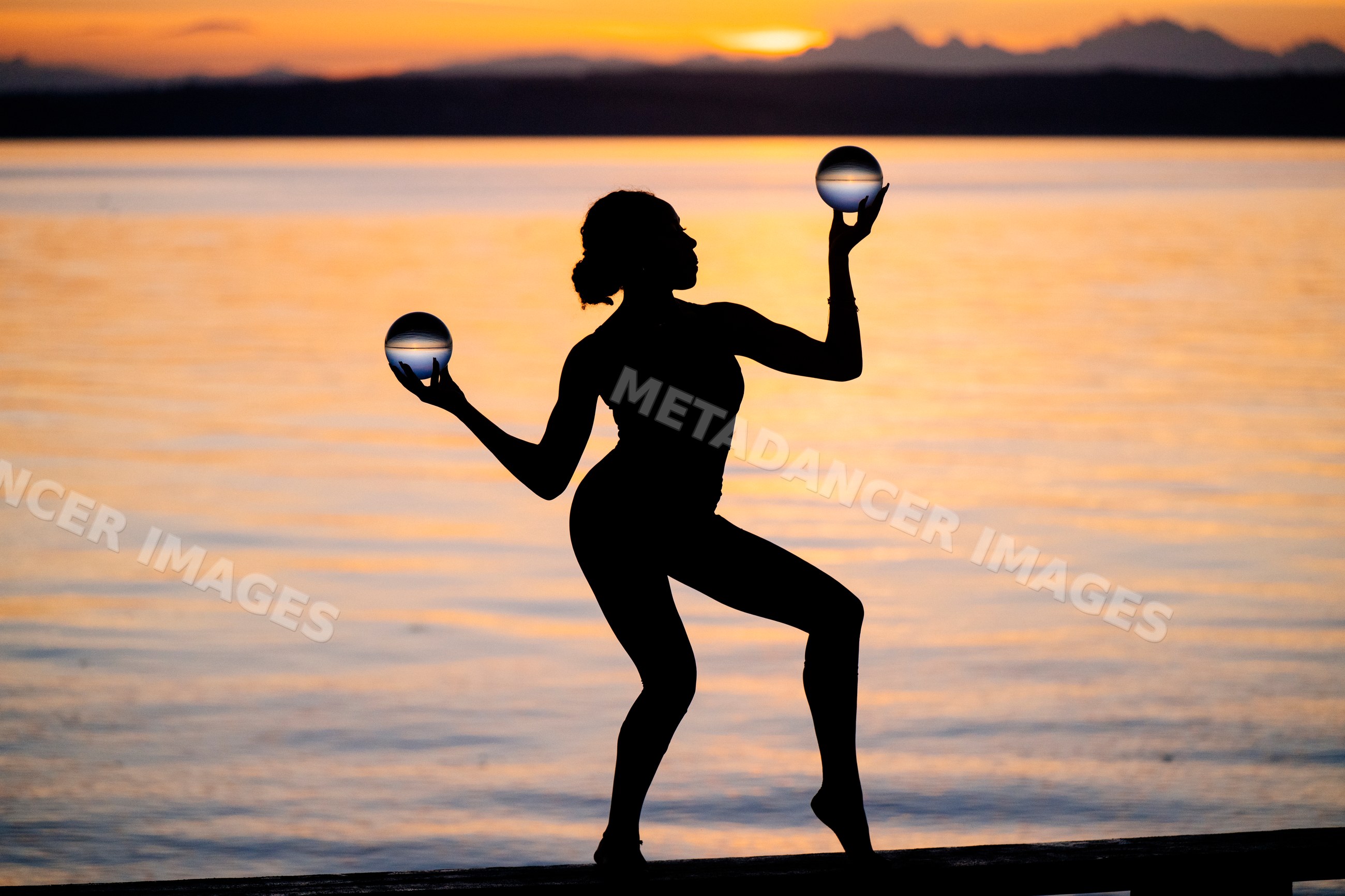 Hispanic woman silhouette balancing glass balls