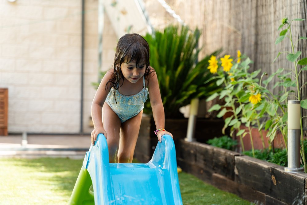Young white girl climbing a blue water slide