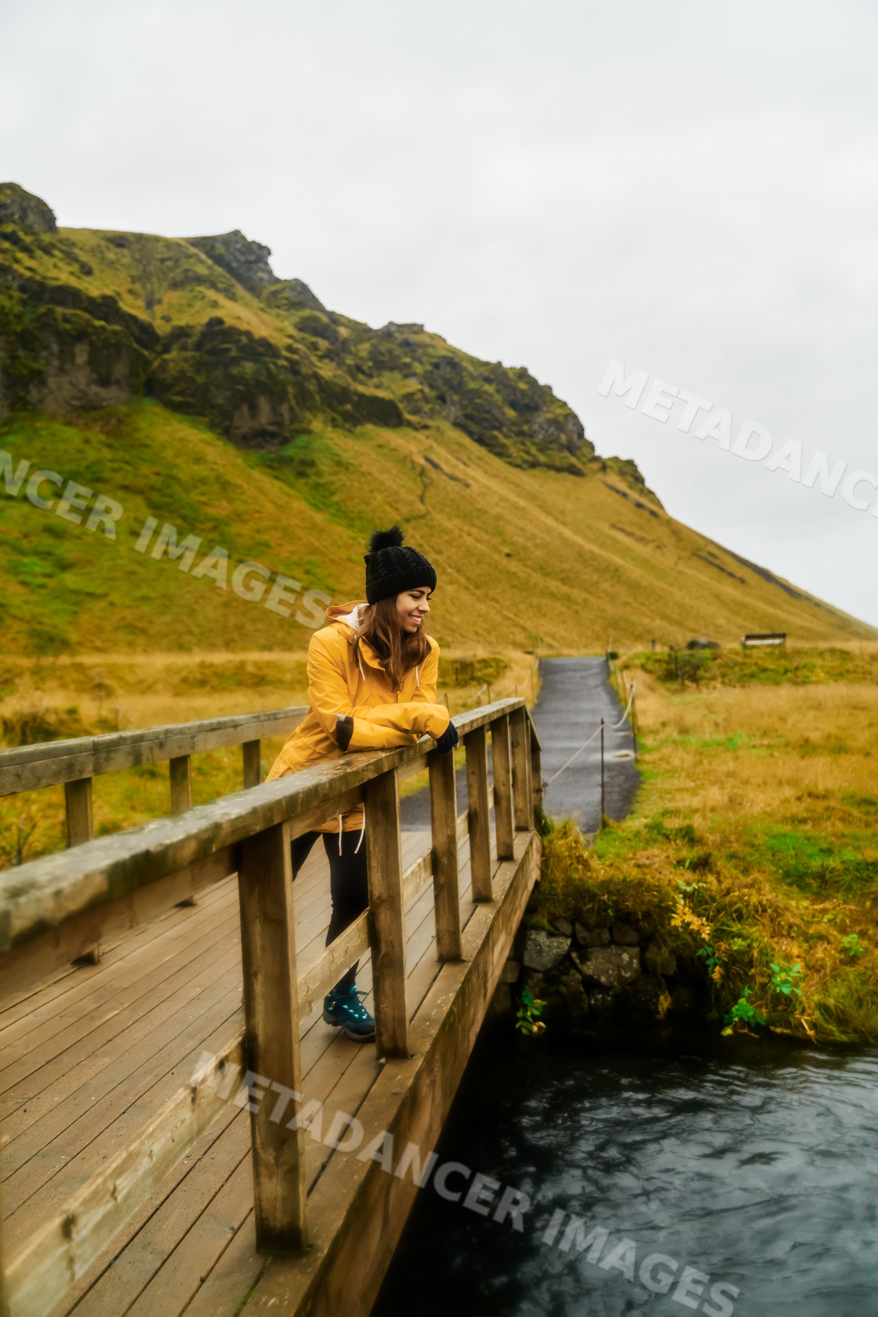 A white woman in a yellow jacket enjoys the scenic nature on a wooden