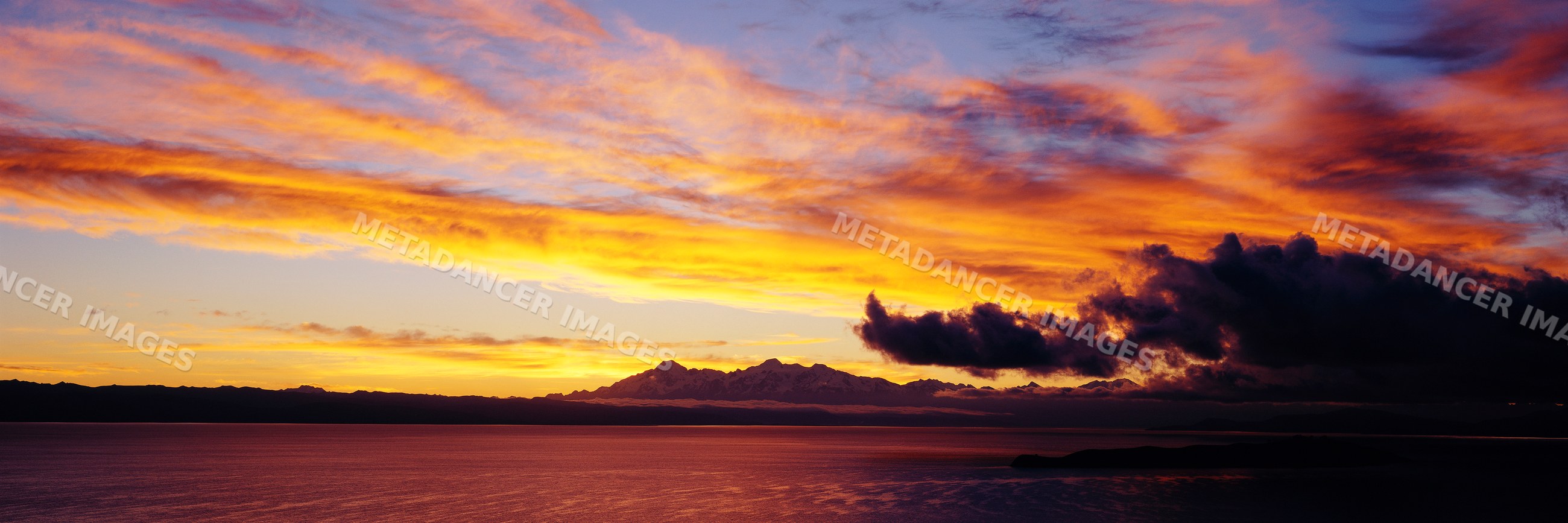 Lake titicaca sunset with dramatic clouds and mountain silhouettes
