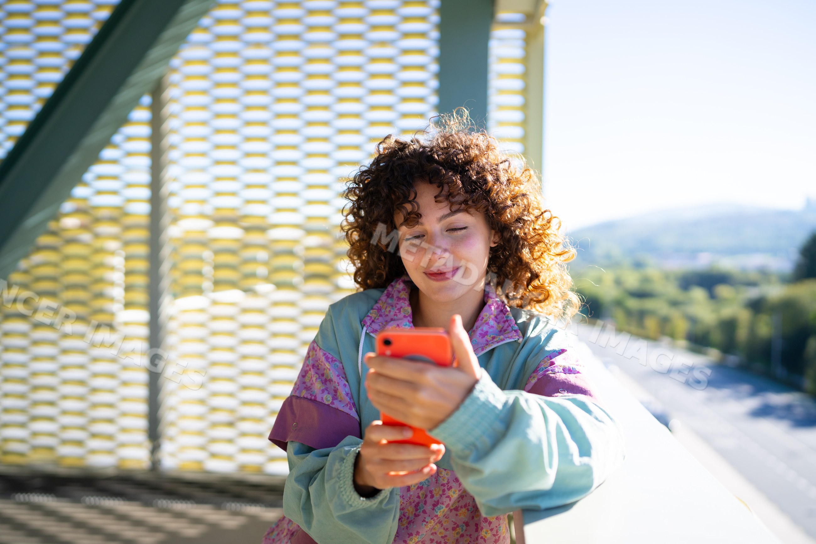 White woman using smartphone on balcony with scenic road view
