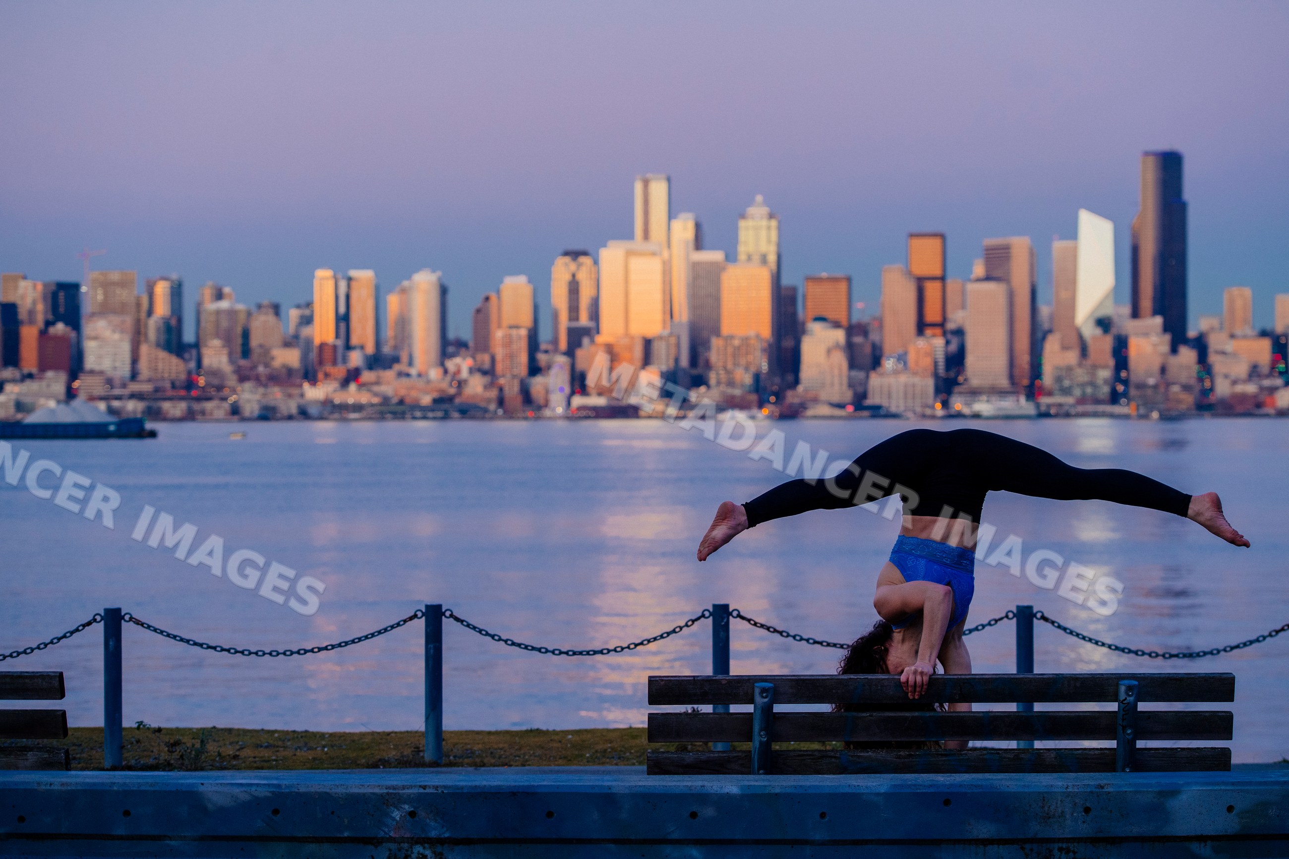 White woman doing handstand yoga pose on bench by Seattle waterfront