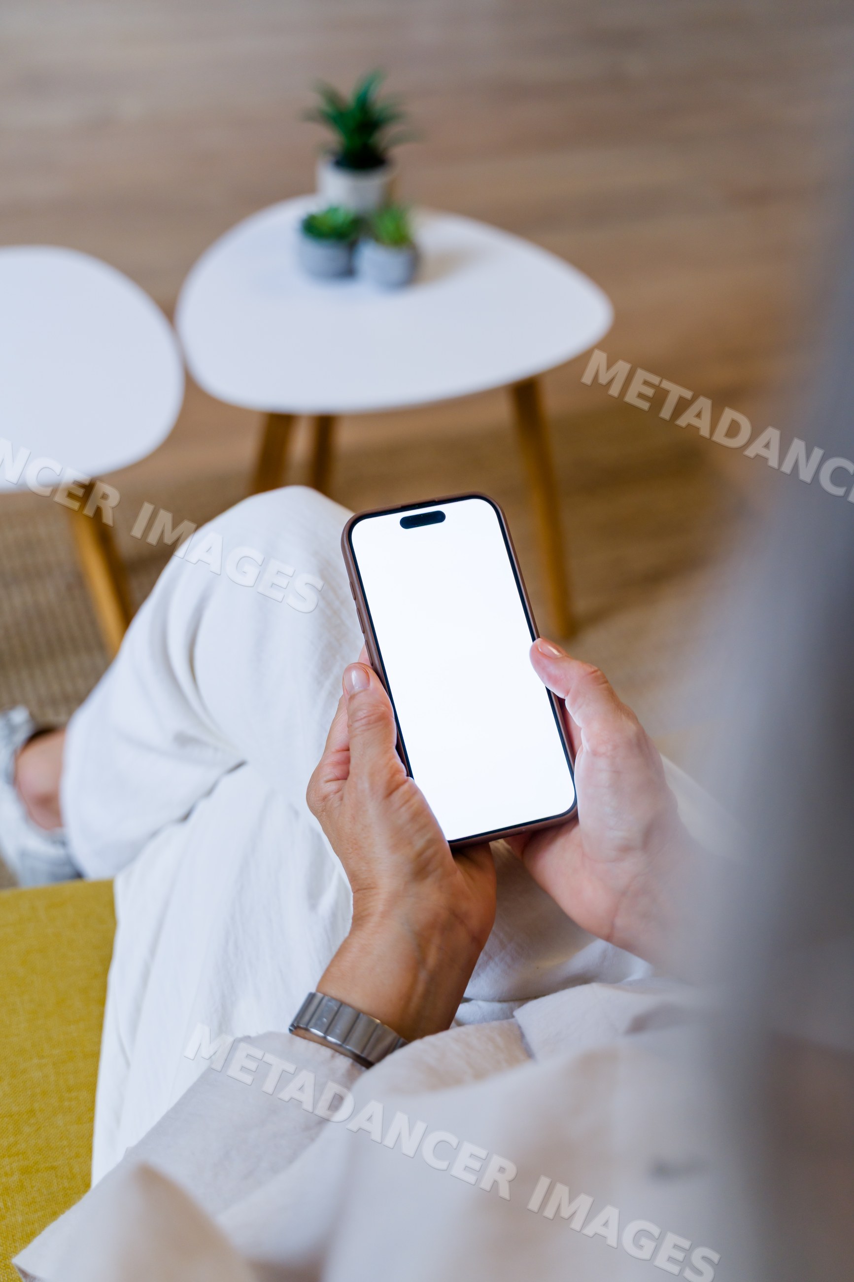 Person holding smartphone with white screen in modern indoor setting