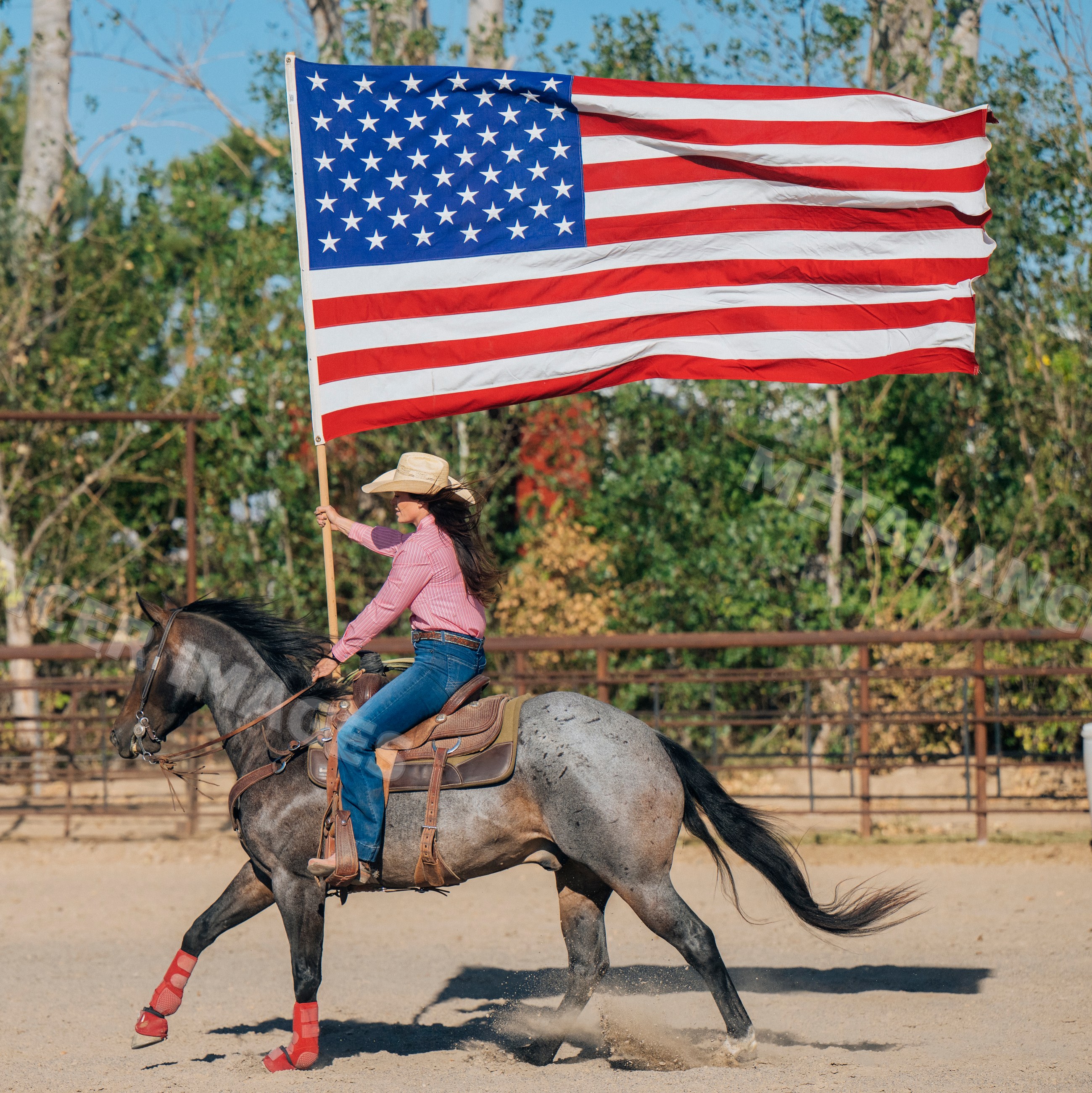 White woman riding horse holding american flag in Southwest USA arena