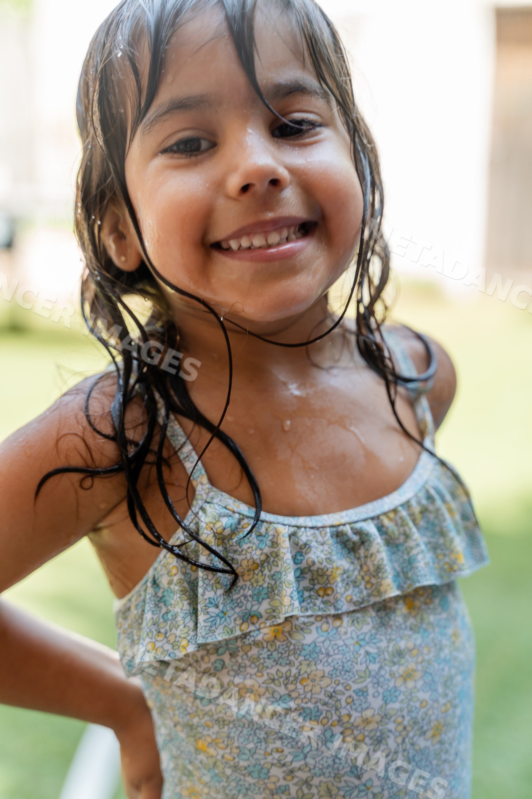 Smiling young white girl enjoying outdoor water play in summer