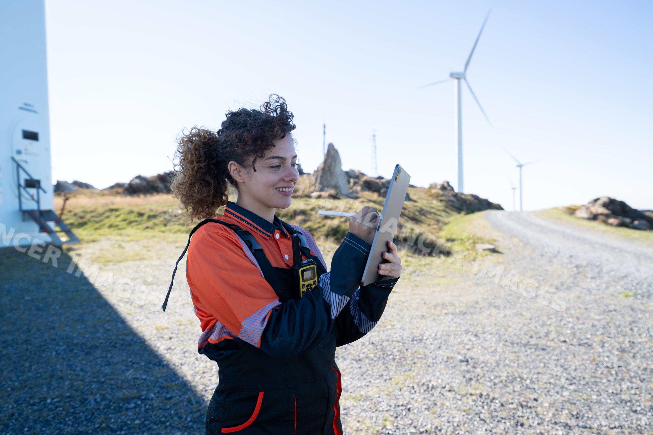 White woman engineer using tablet at wind farm in Galicia, Spain