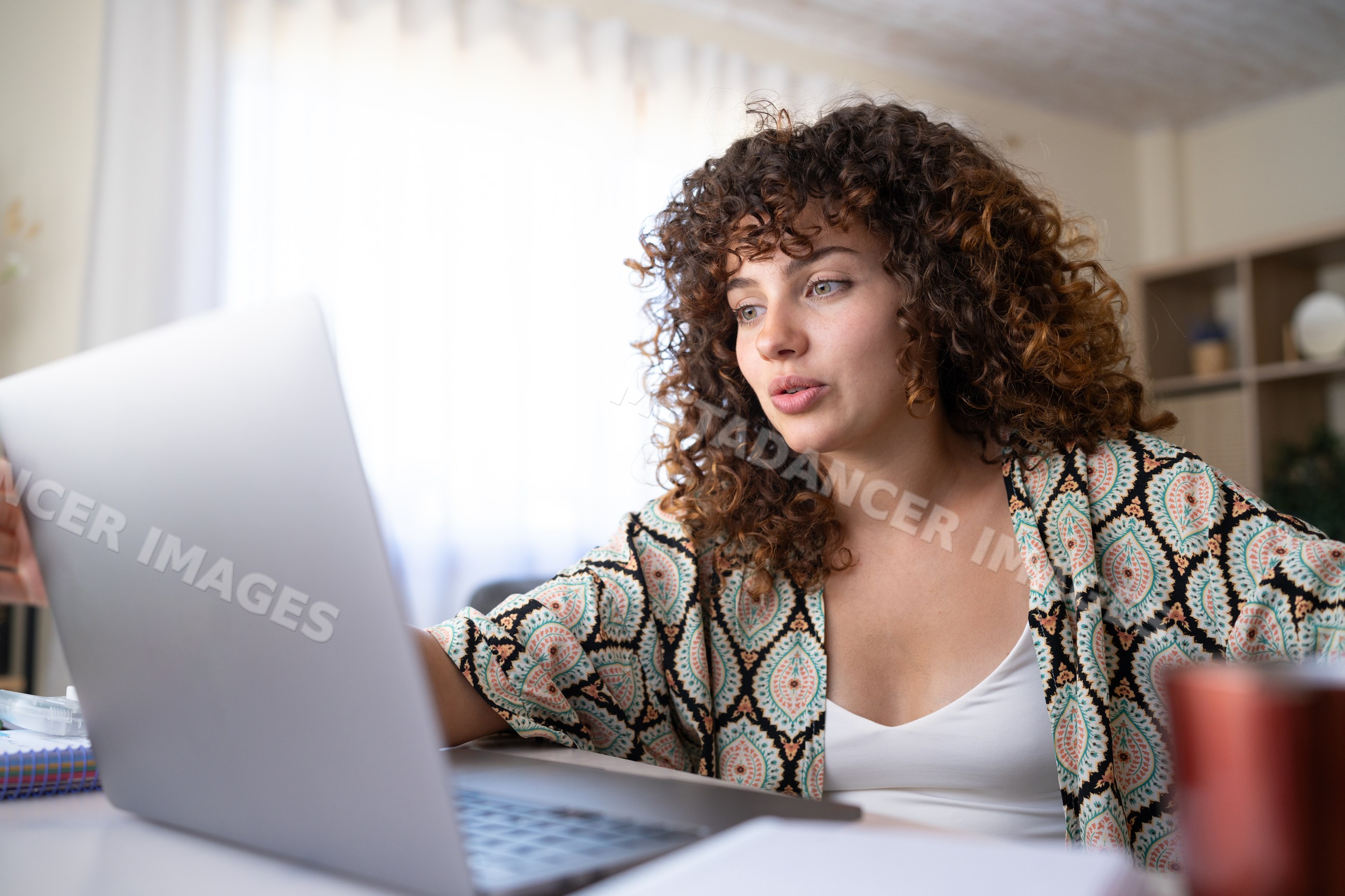 White woman engaged in video call using laptop in home office