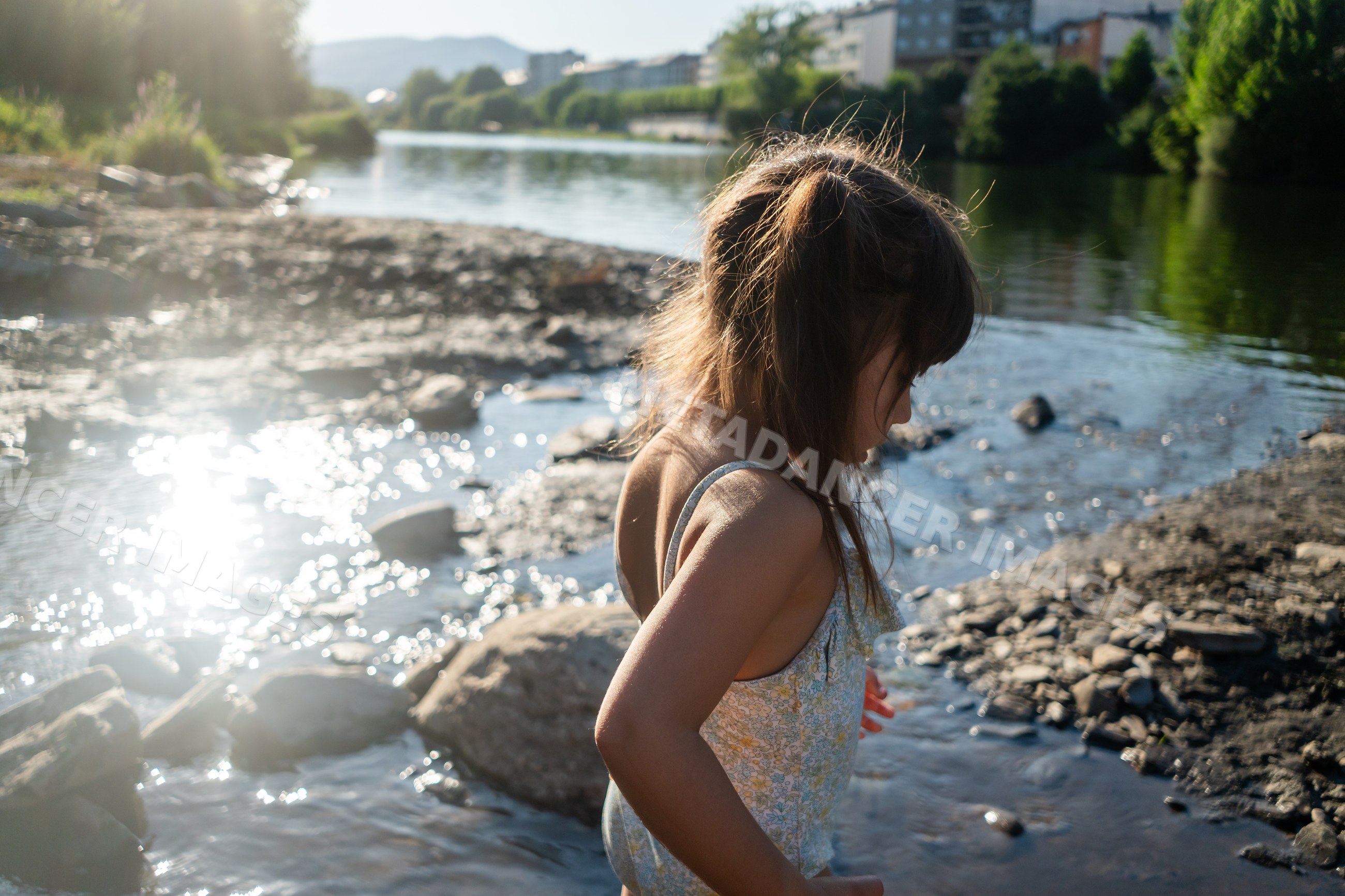 A young white girl playing by the rocky riverbank