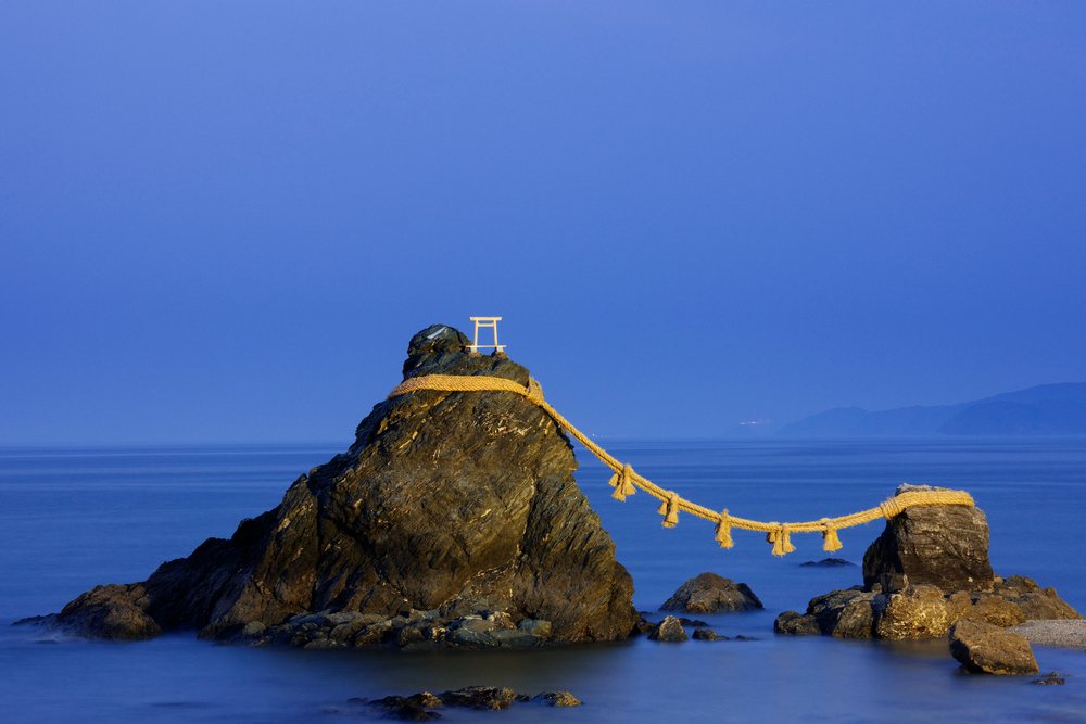 Meoto iwa tidal rocks linked by shimenawa rope with torii gate