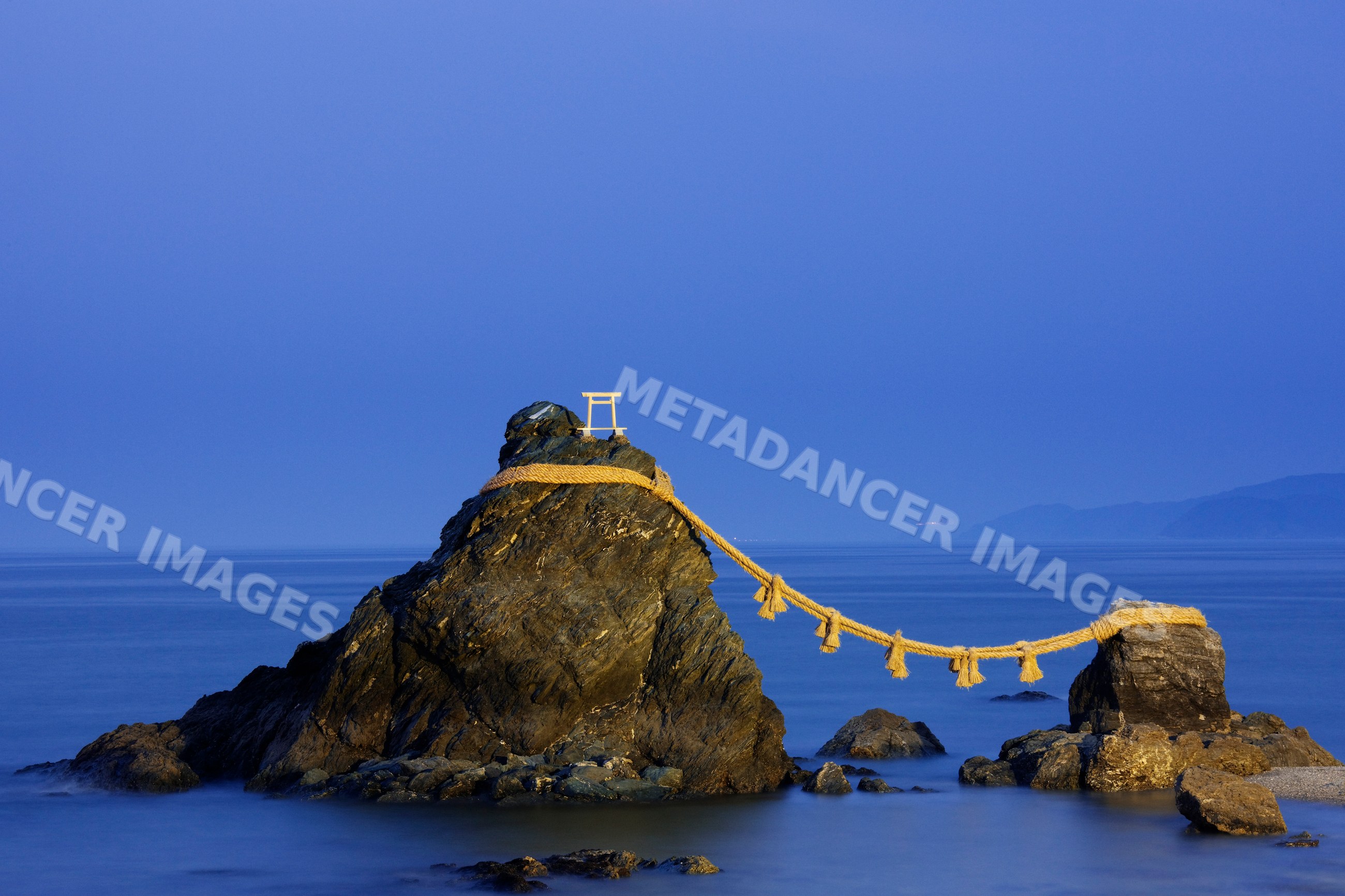 Meoto iwa tidal rocks linked by shimenawa rope with torii gate