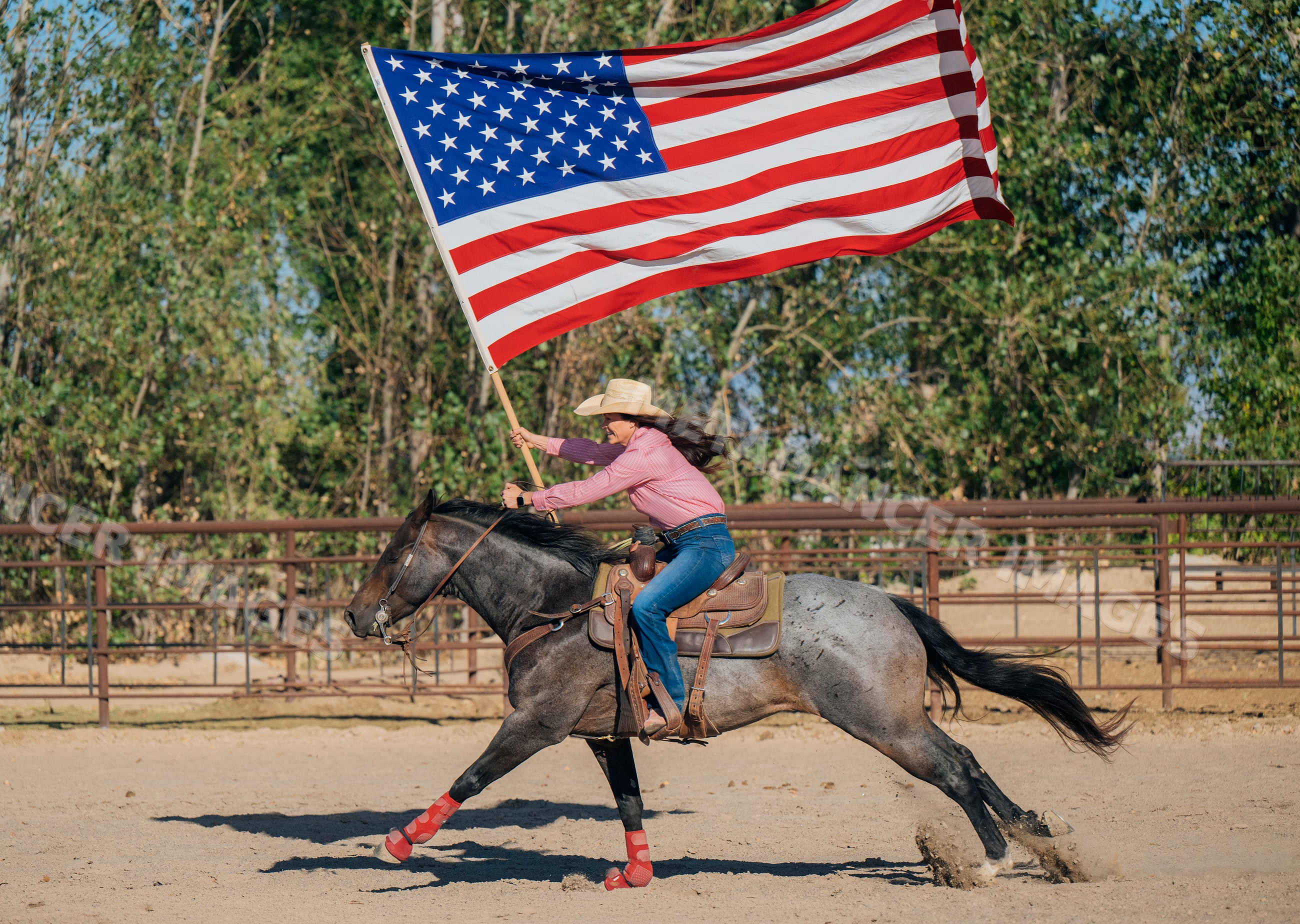 Female rider galloping horse with american flag in outdoor arena