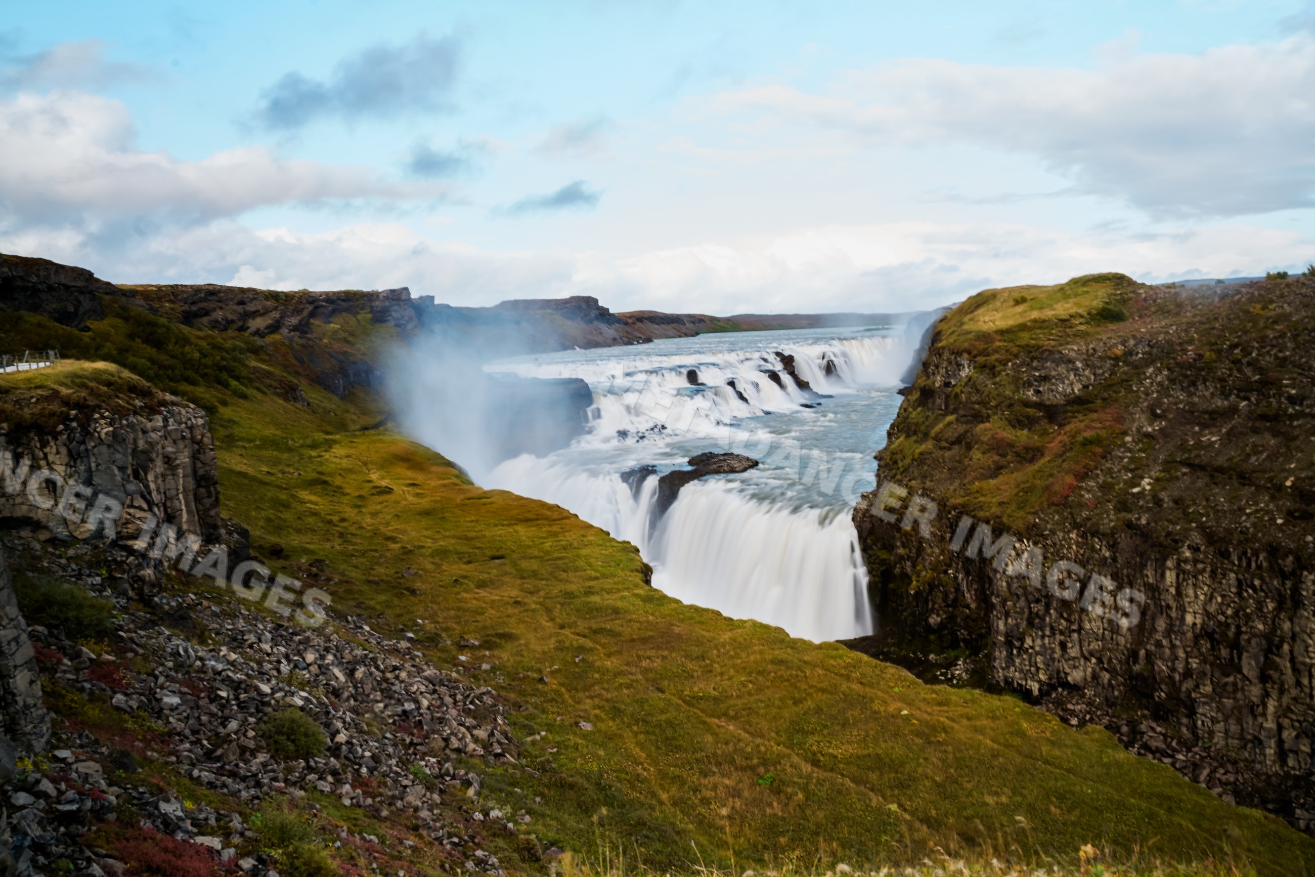 A waterfall cascades between basalt cliffs
