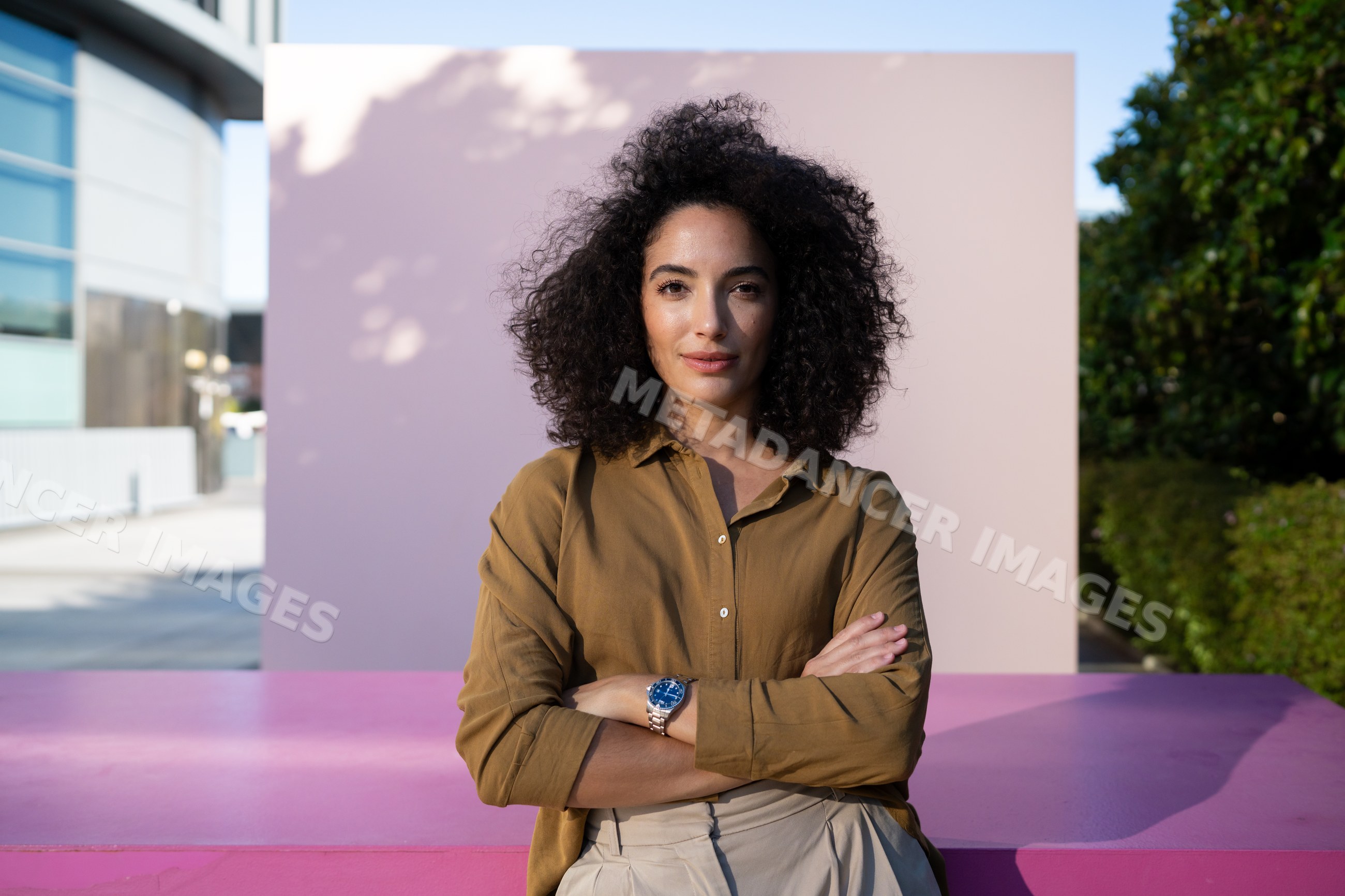 Confident woman posing outdoors by pink wall