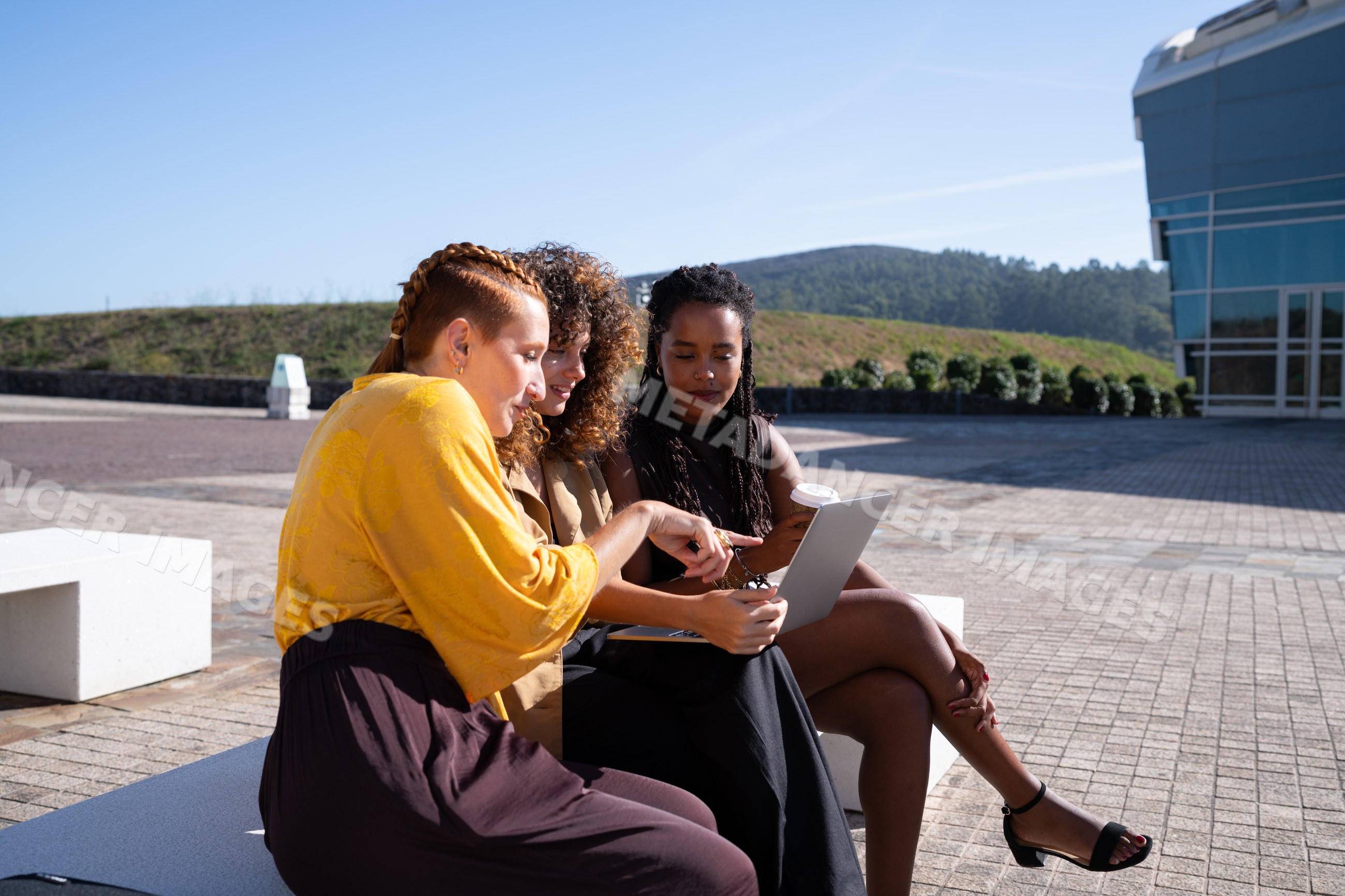 Three African American and white women discussing with tablet outdoors