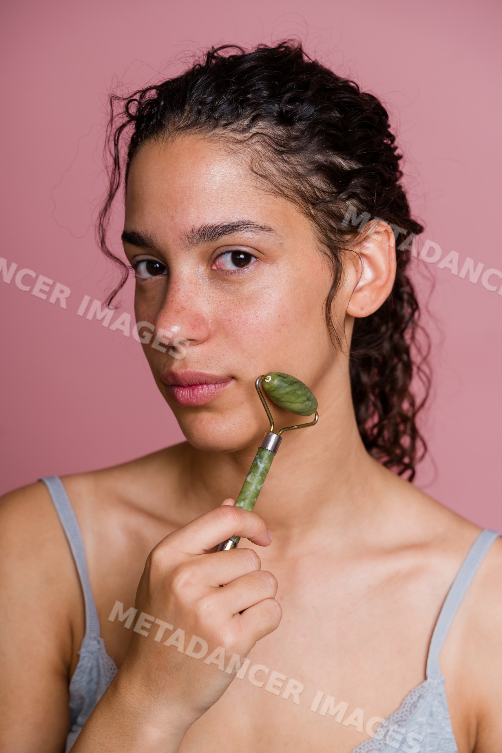 Hispanic woman using jade roller for facial massage and skincare