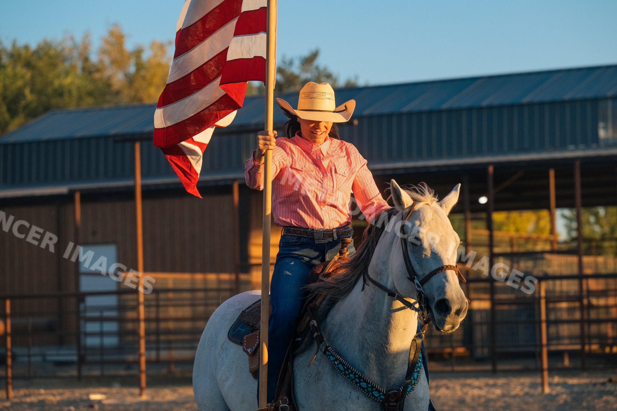 White woman riding horse holding american flag at Southwest USA ranch