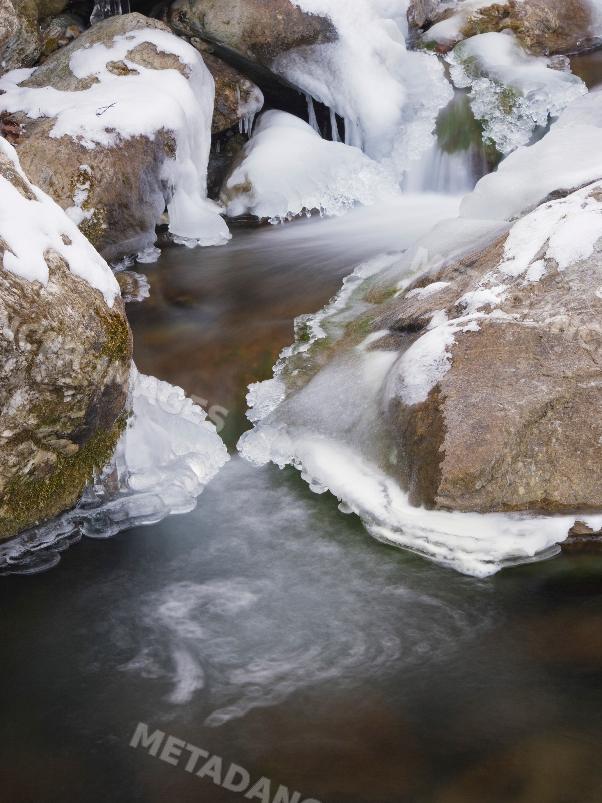 Stream flowing around snow-covered rocks landscape
