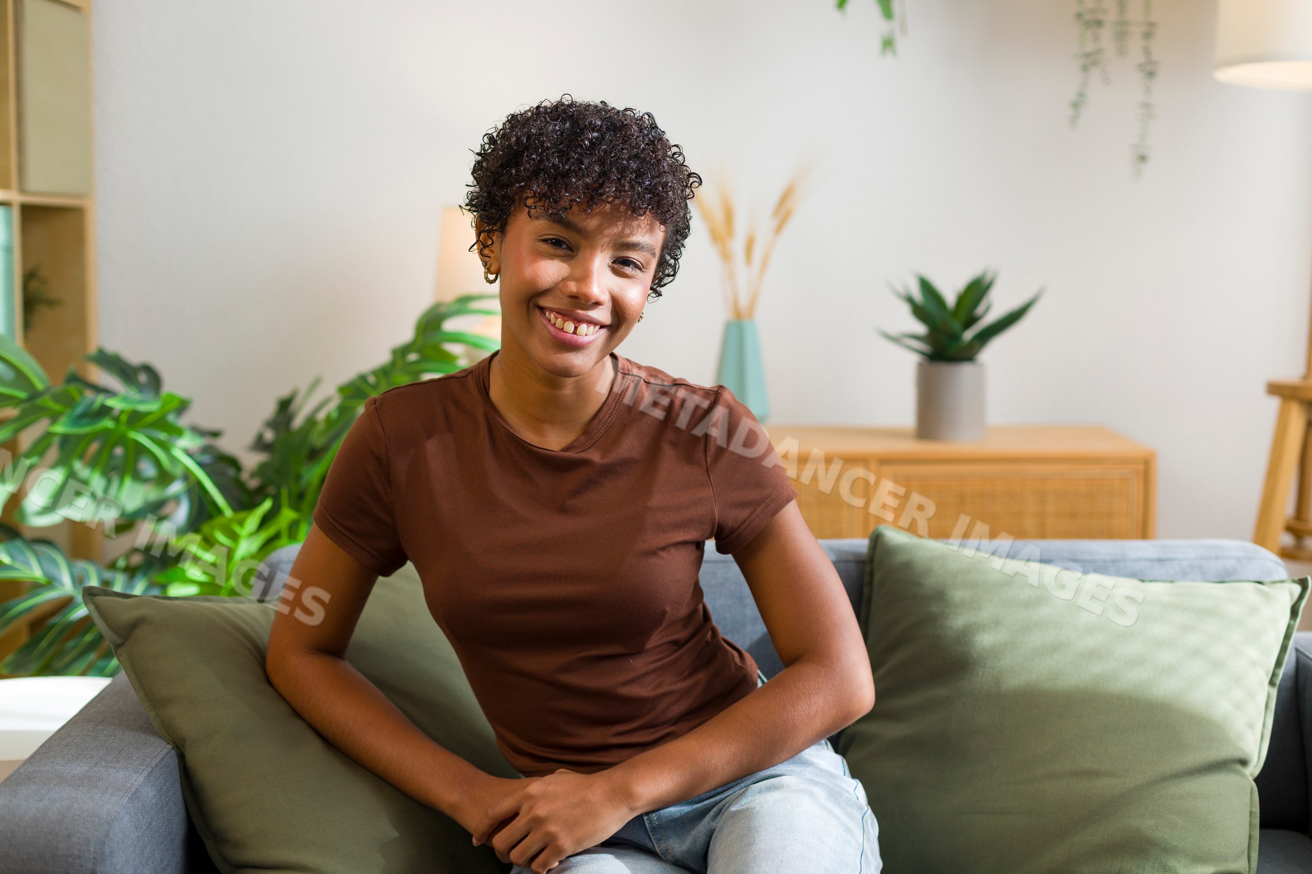 Young African American woman seated on couch smiling indoors