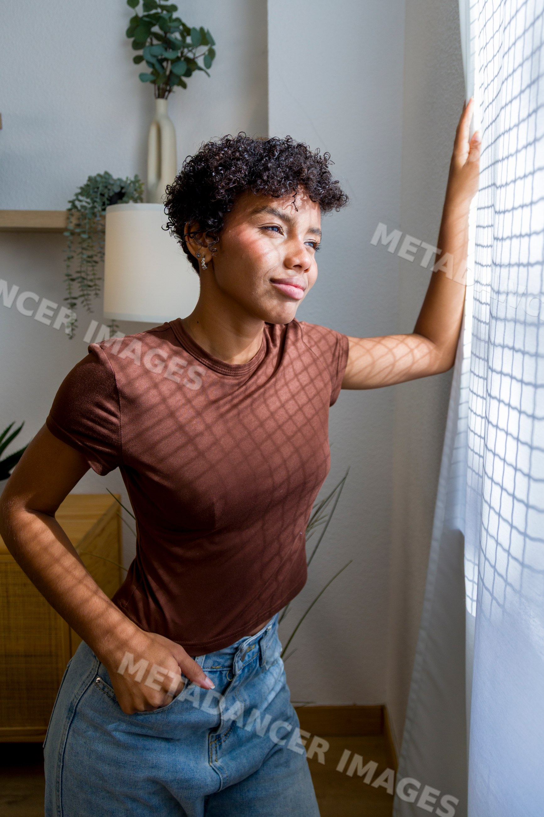 Young African American woman standing indoors looking thoughtfully out