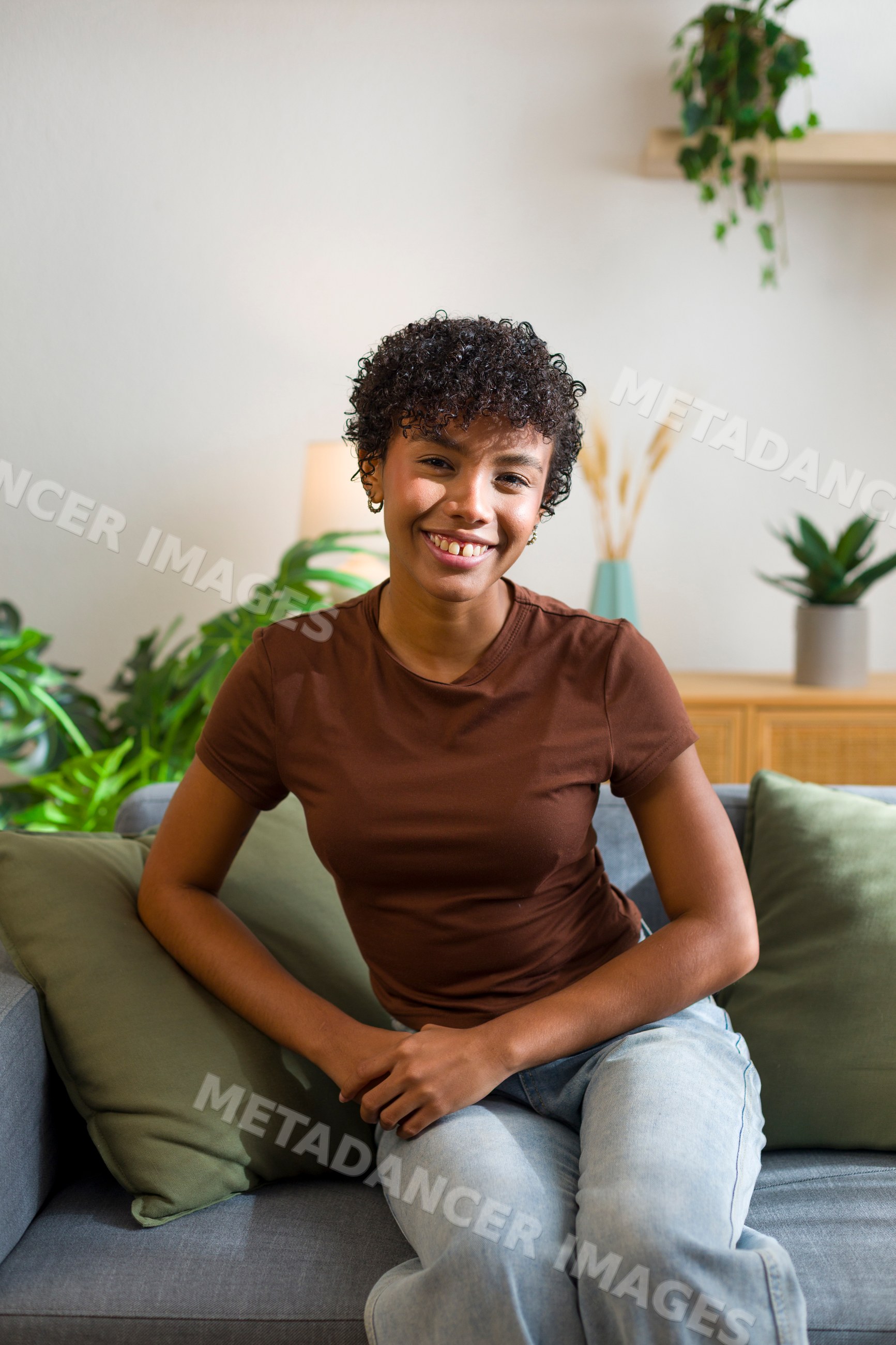 Young African American woman sitting happily on sofa