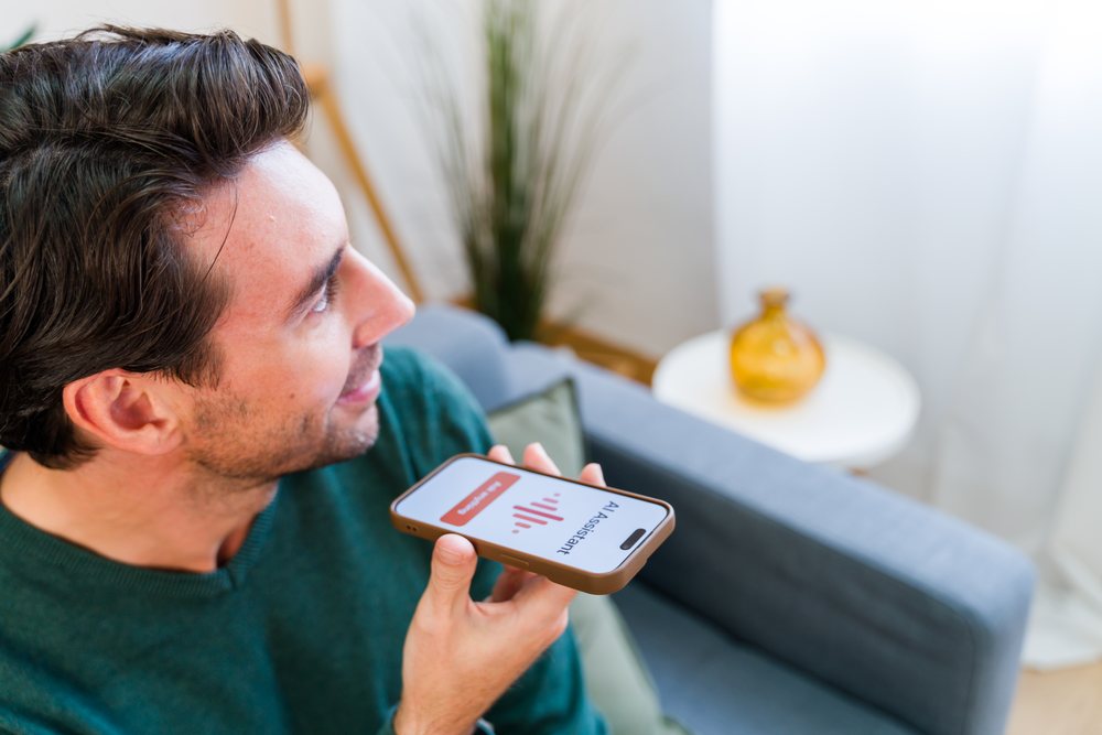 White man using smartphone voice assistant in living room