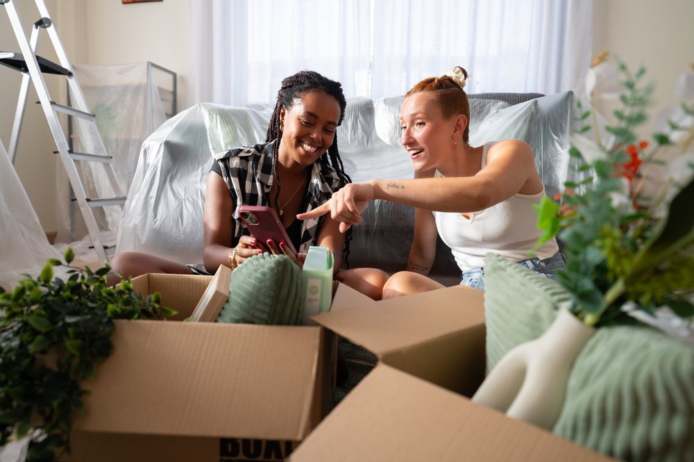 Two African American and white women unpack boxes and enjoy a joyful