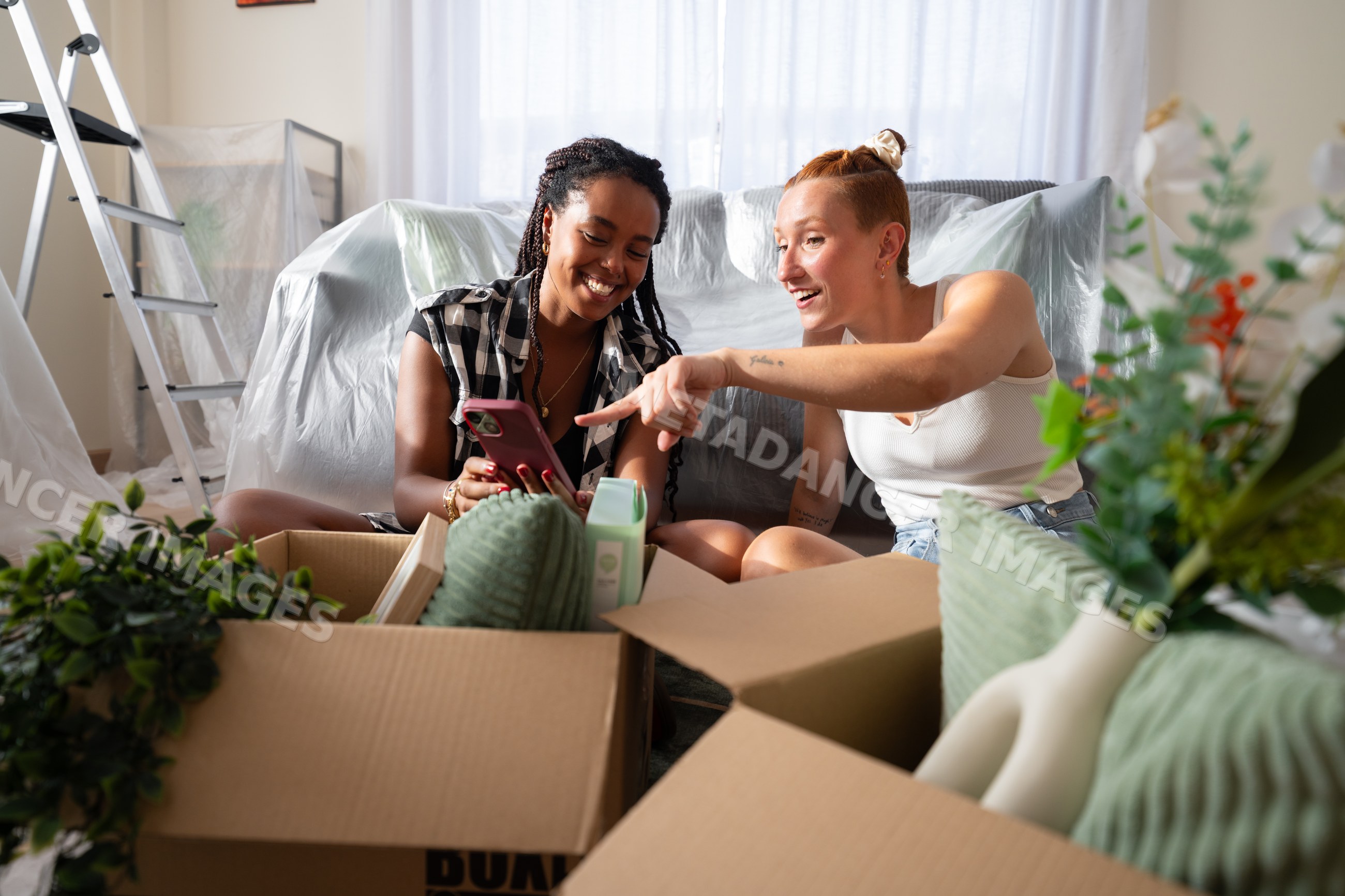 Two African American and white women unpack boxes and enjoy a joyful