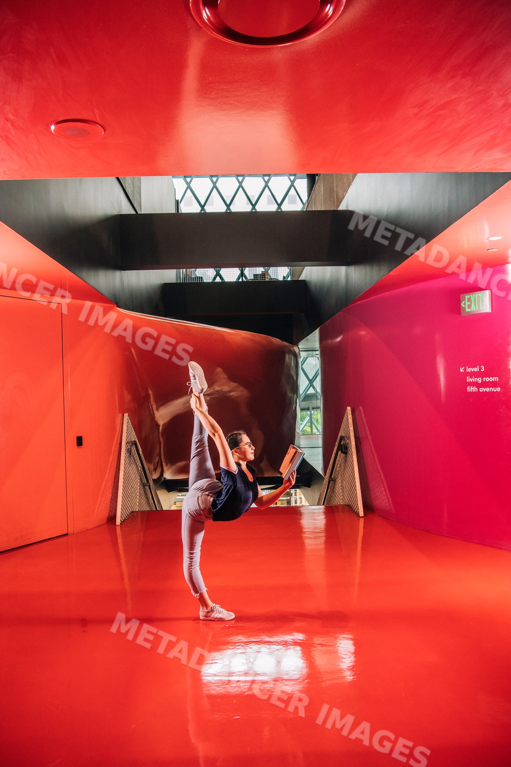 A woman reads a book practicing yoga in Seattle public library hallway
