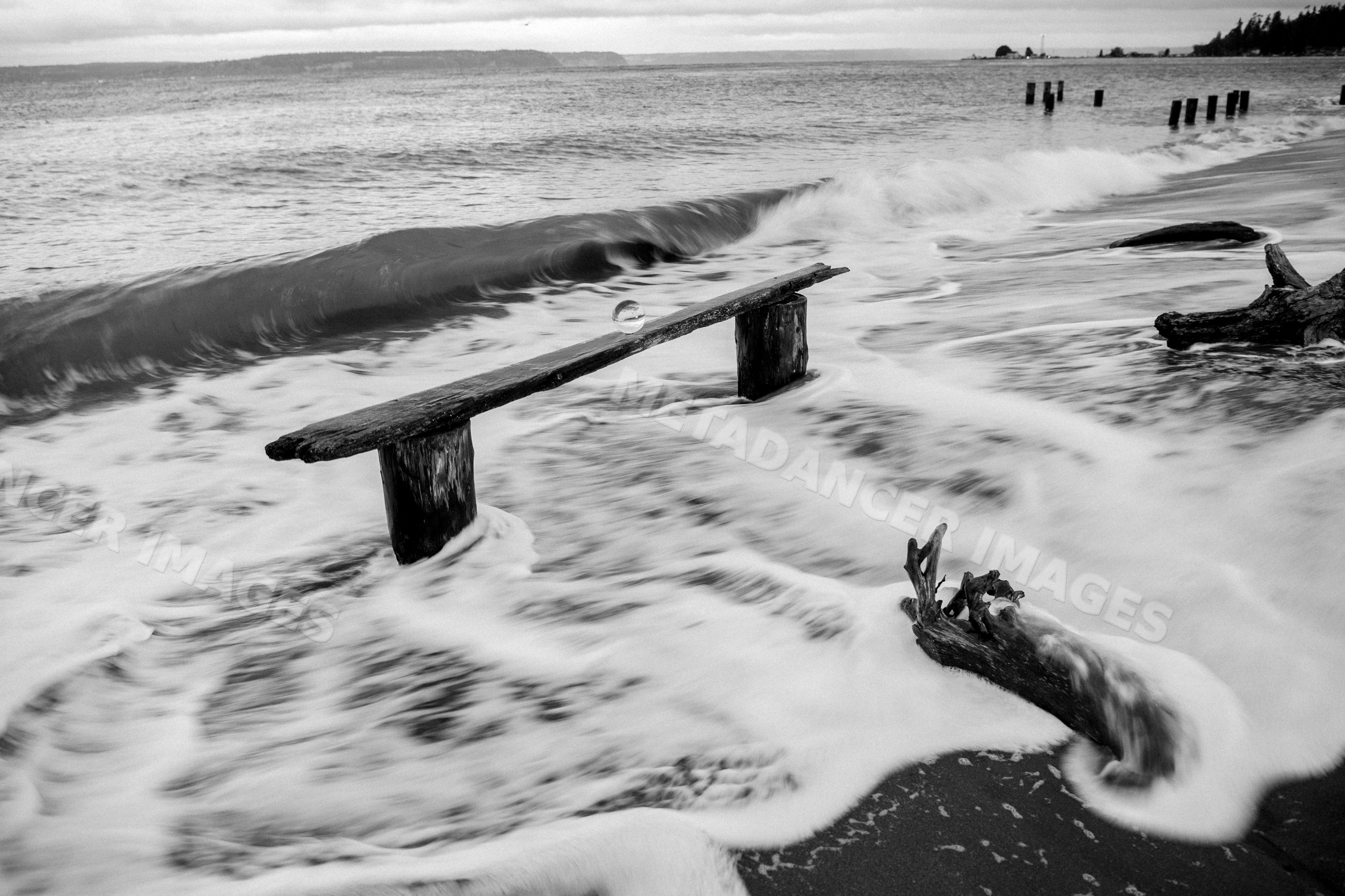 Waves crashing over driftwood and wooden beam