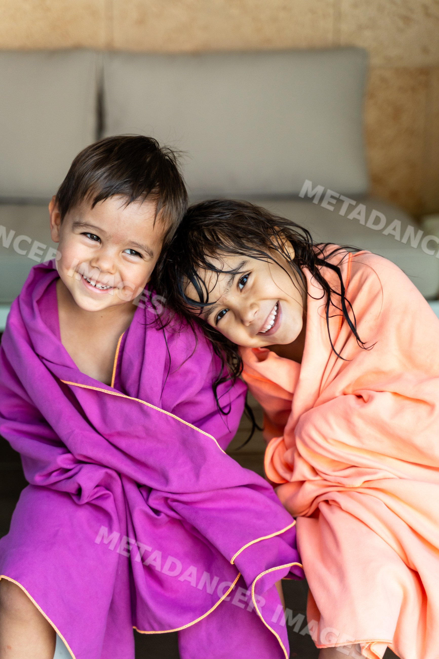 Two white children wrapped in towels smiling indoors in Madrid, Spain