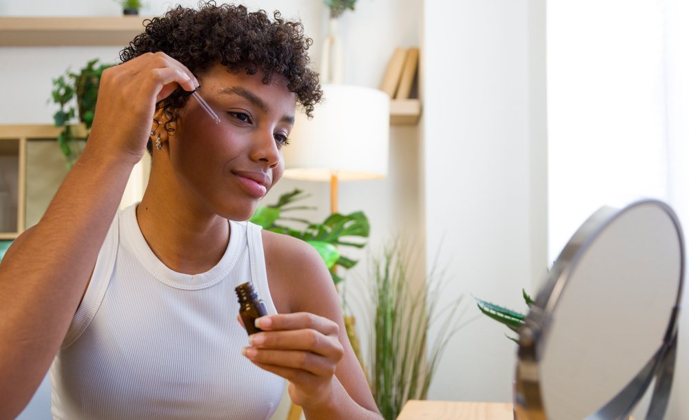 African American woman applying face serum with dropper
