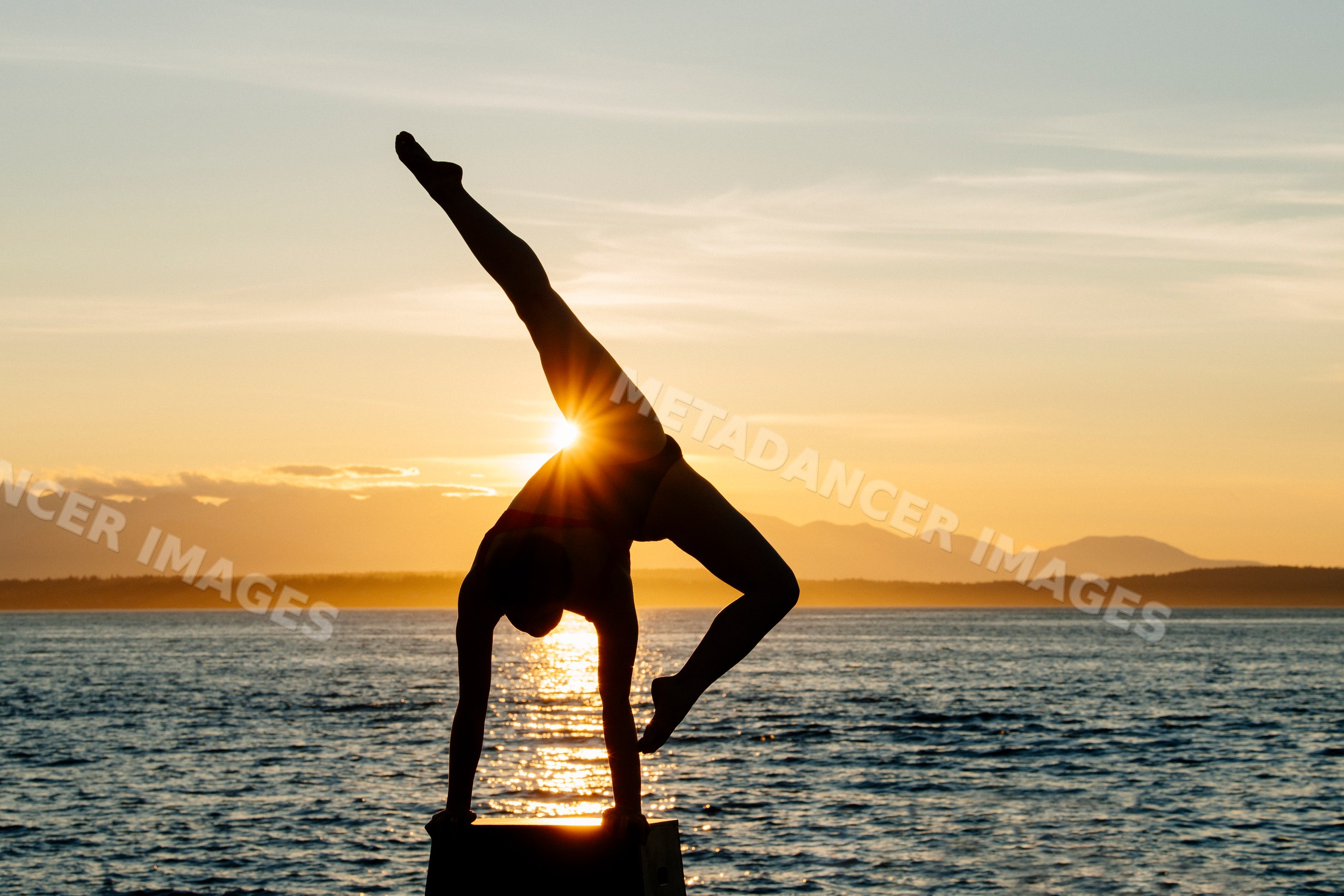 White woman performing handstand by ocean