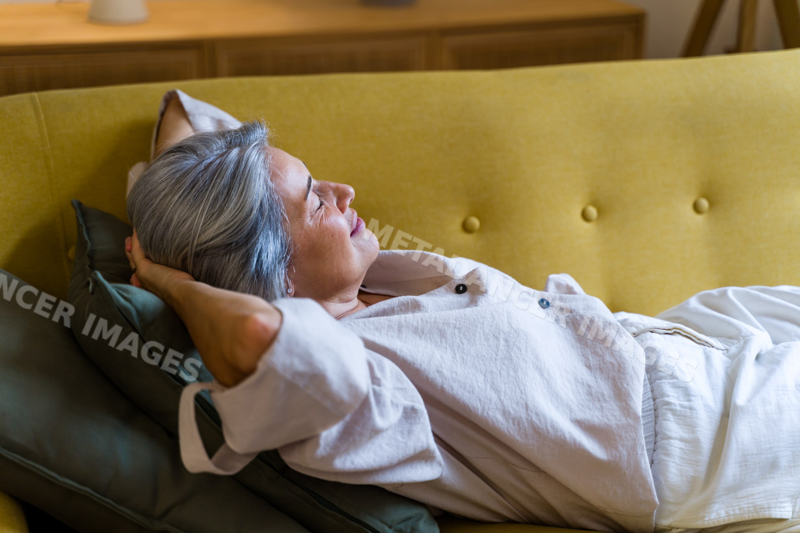 White woman relaxing on a yellow sofa in a calm indoor setting