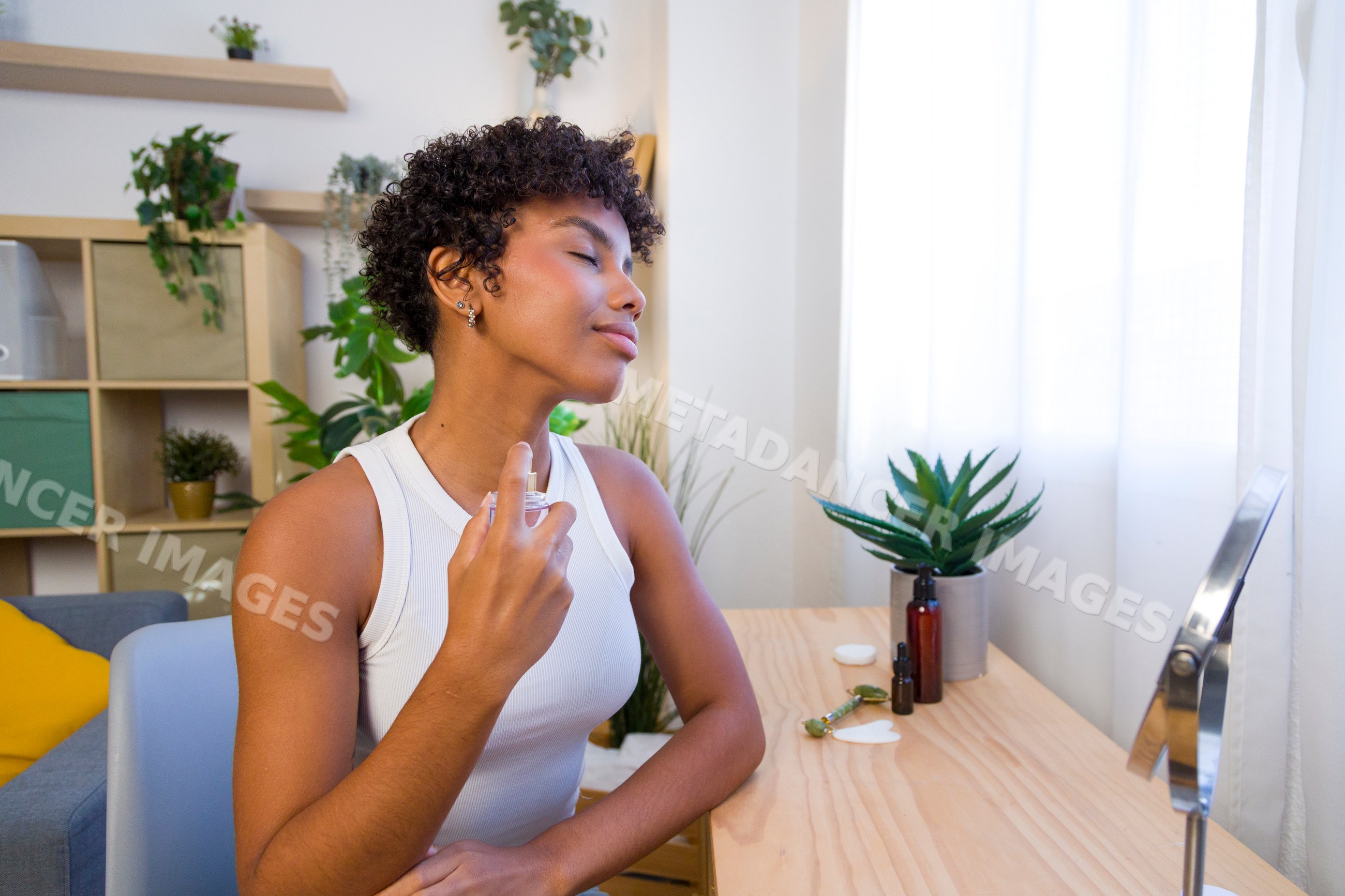 Young African American woman spraying perfume