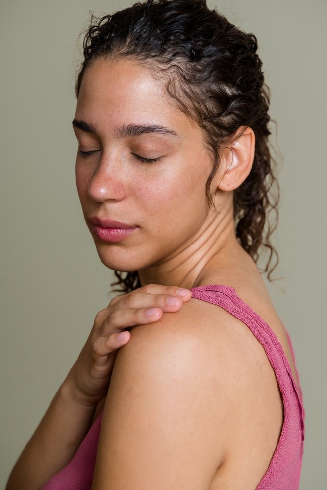 Hispanic woman gently touching shoulder in serene studio portrait