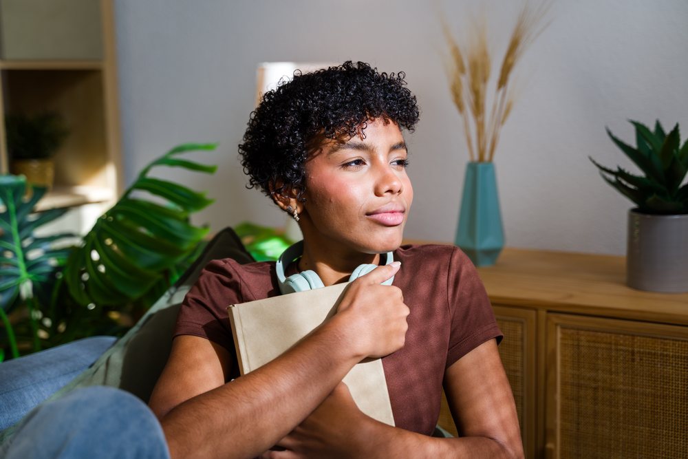 African American woman hugging book with headphones