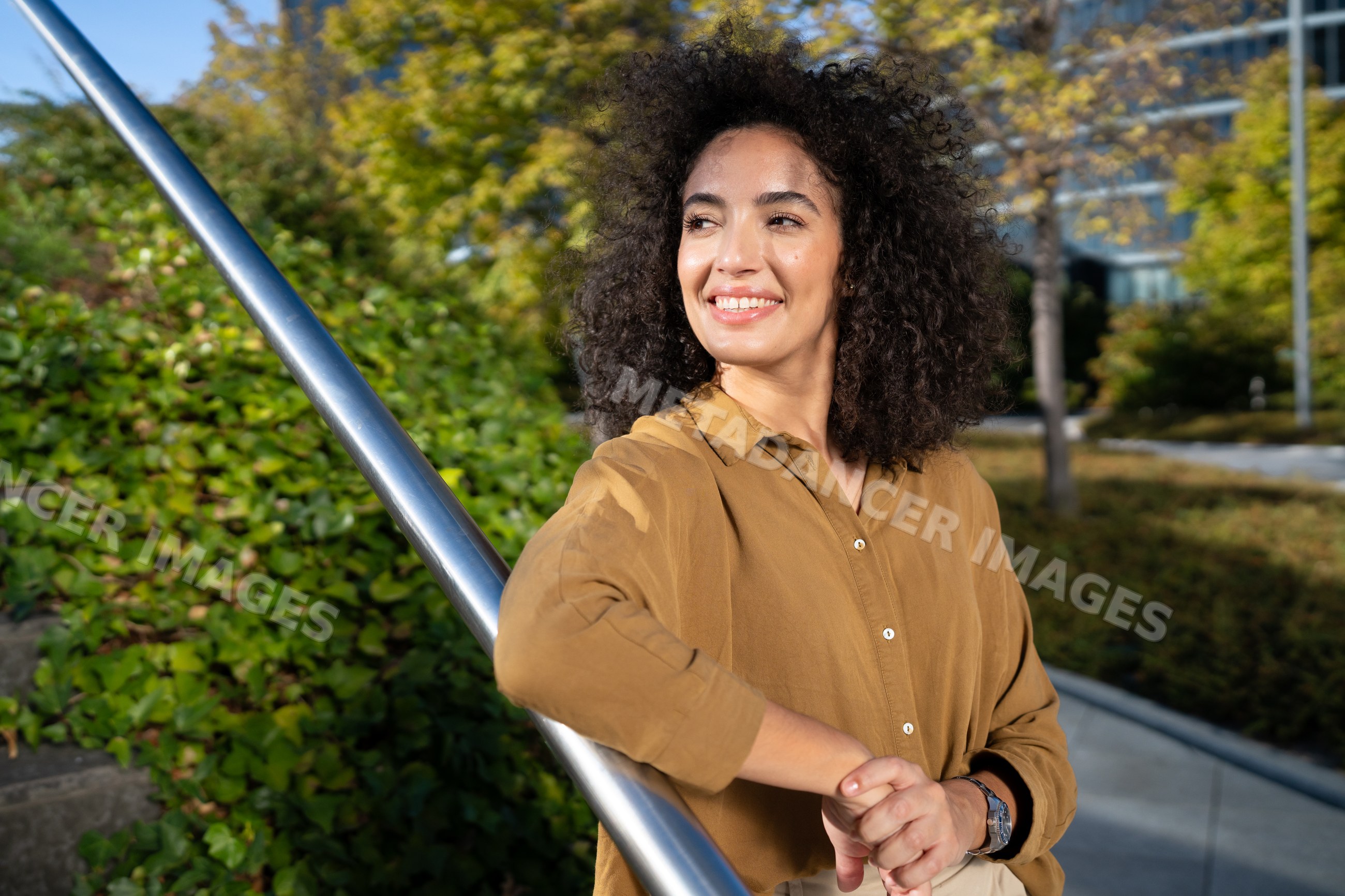 Woman smiling outdoors leaning on handrail in urban park in Madrid