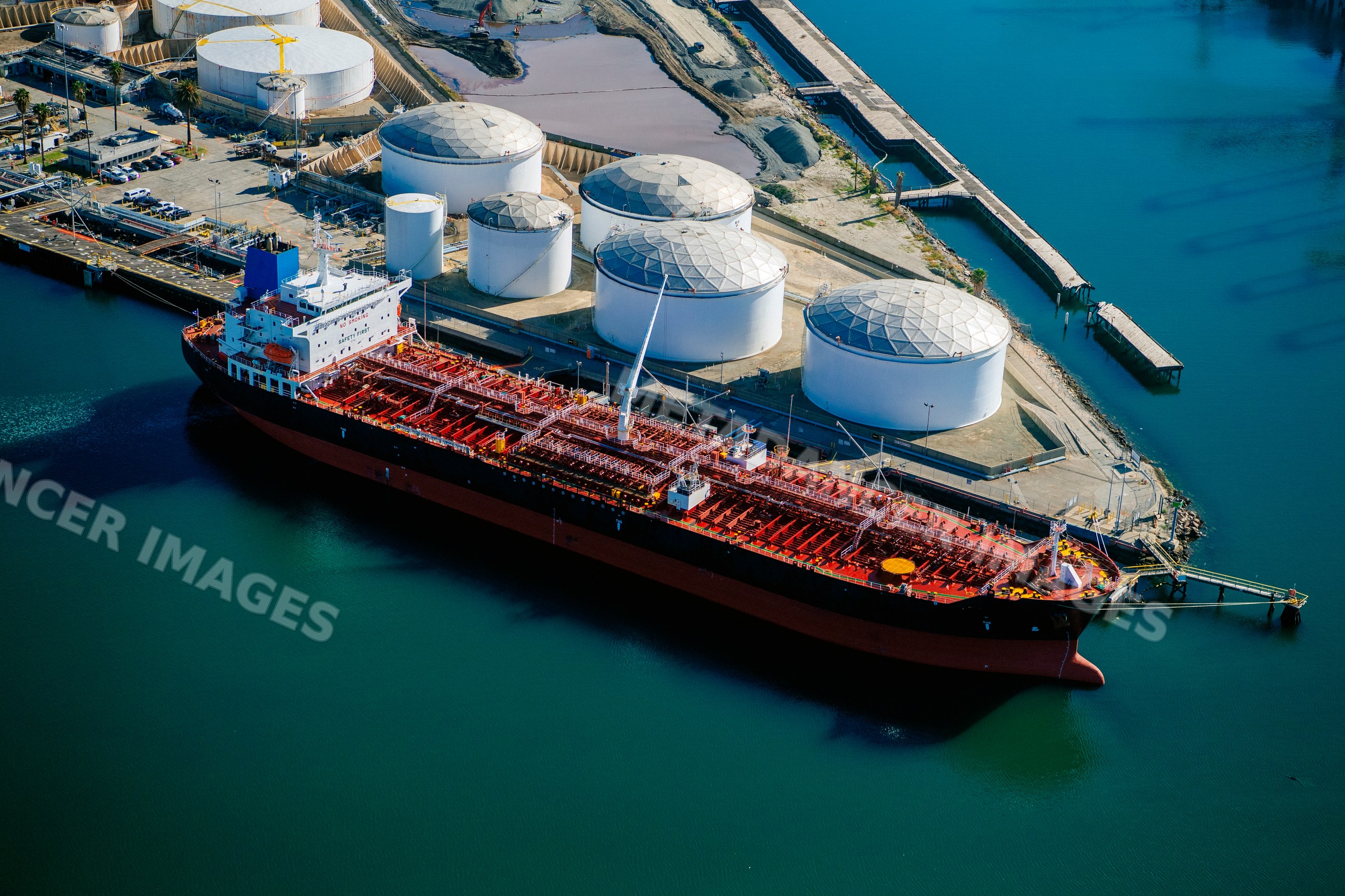 Oil tanker docked at liquid storage tanks in a beach
