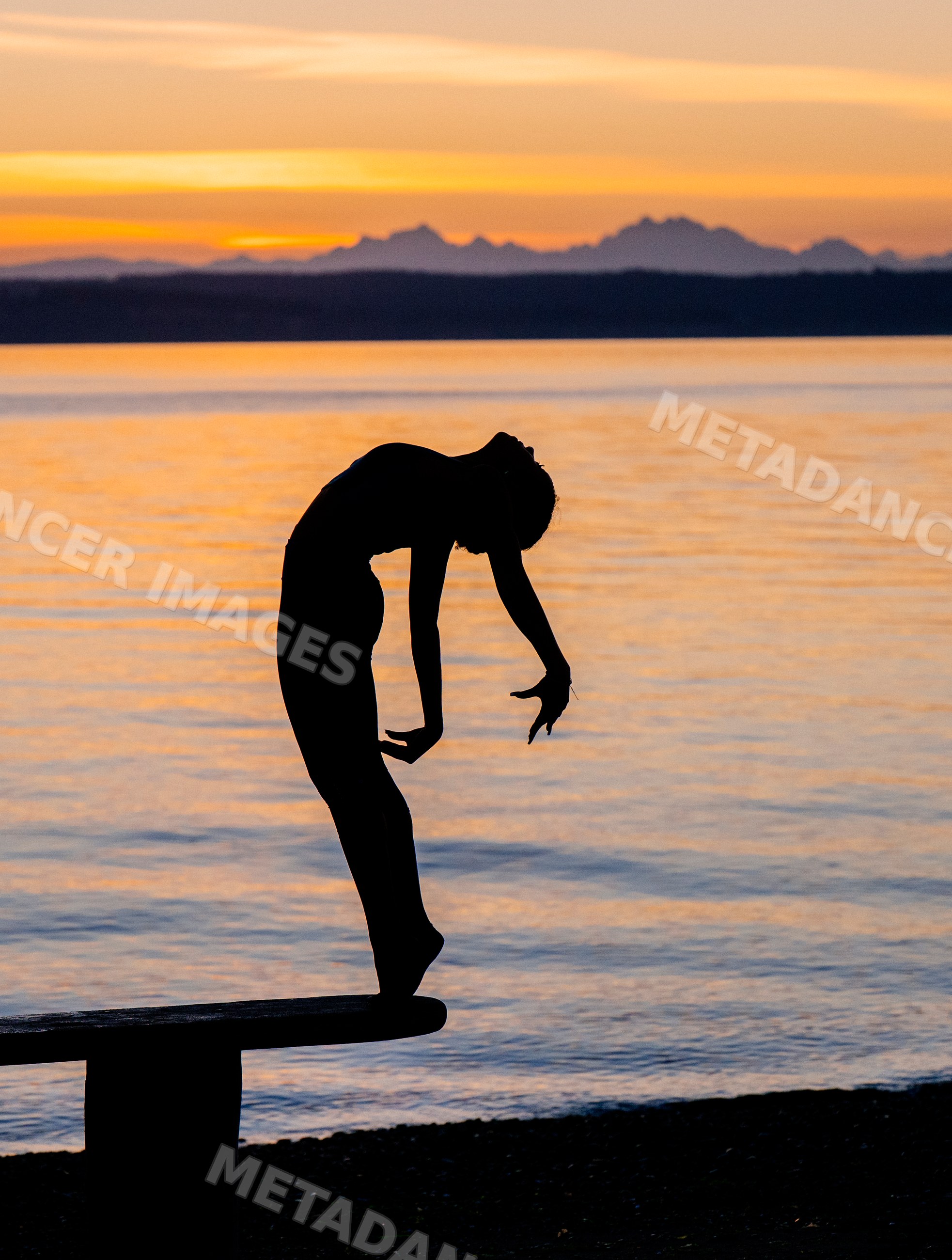Silhouette of Hispanic woman practicing yoga backbend on bench