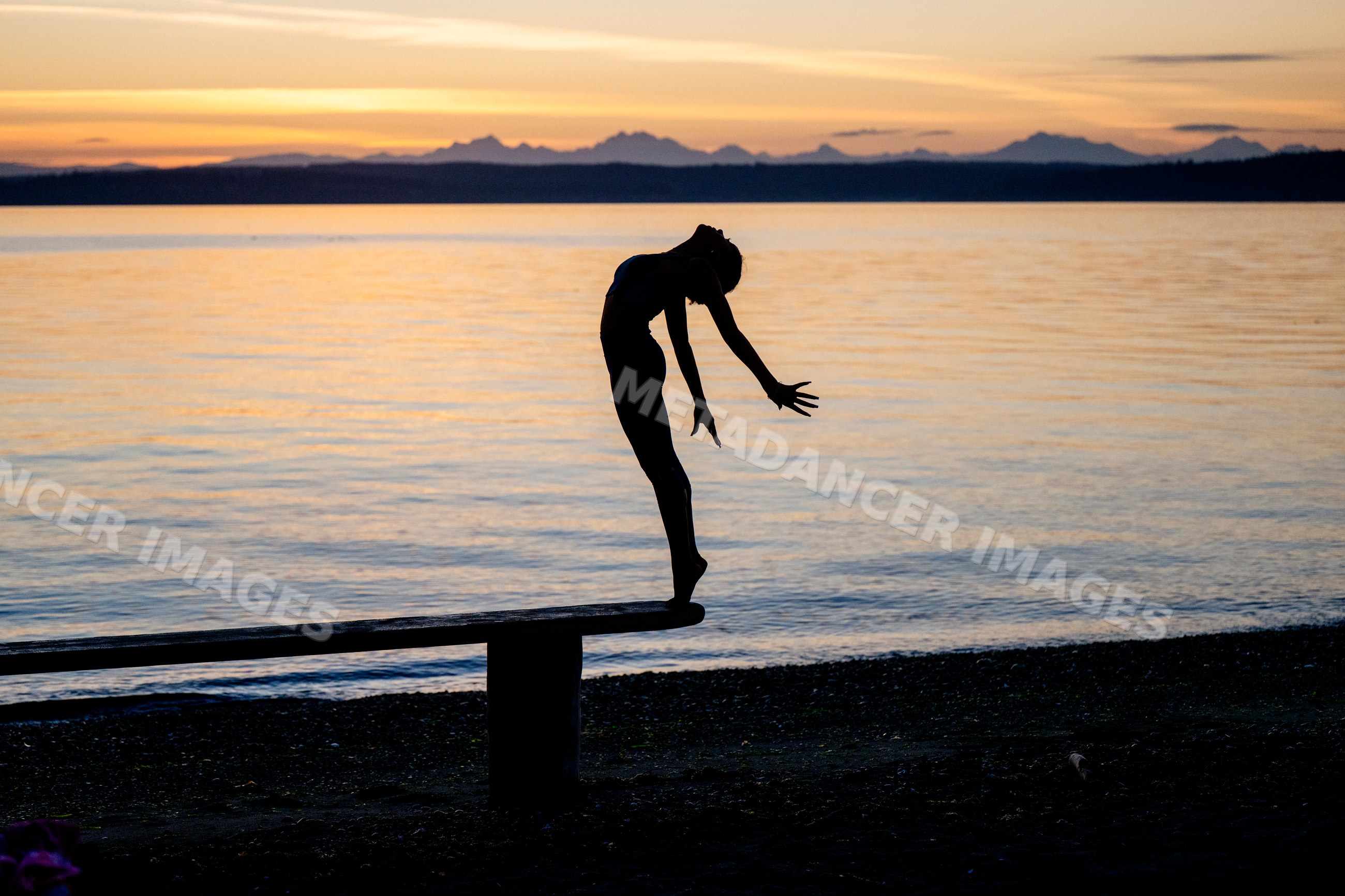 Hispanic woman practicing yoga acrobatics balancing on bench by lake