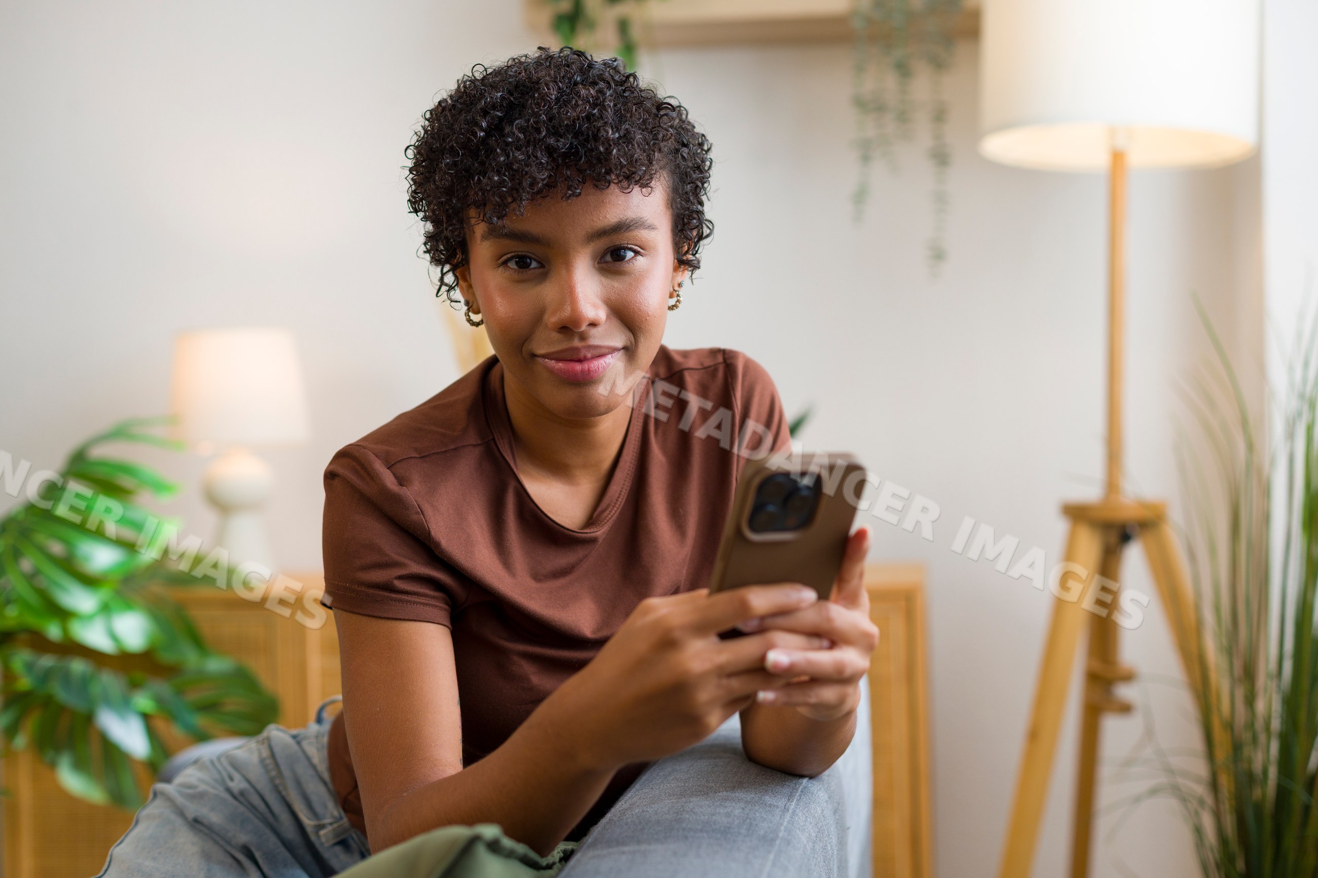 Young African American woman using smartphone in home interior setting