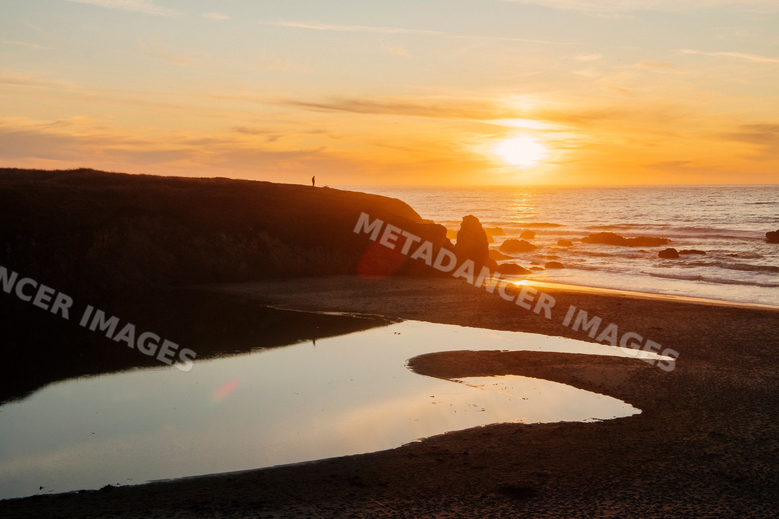 Sunset over rocky beach cliffs and ocean shore reflection