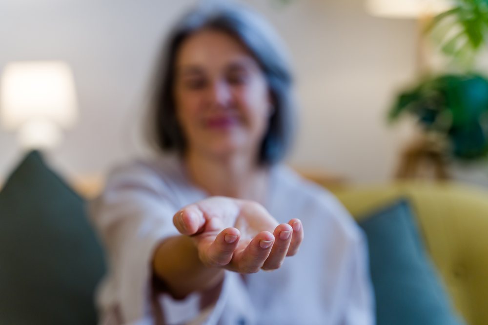 White woman extending hand indoors in living room