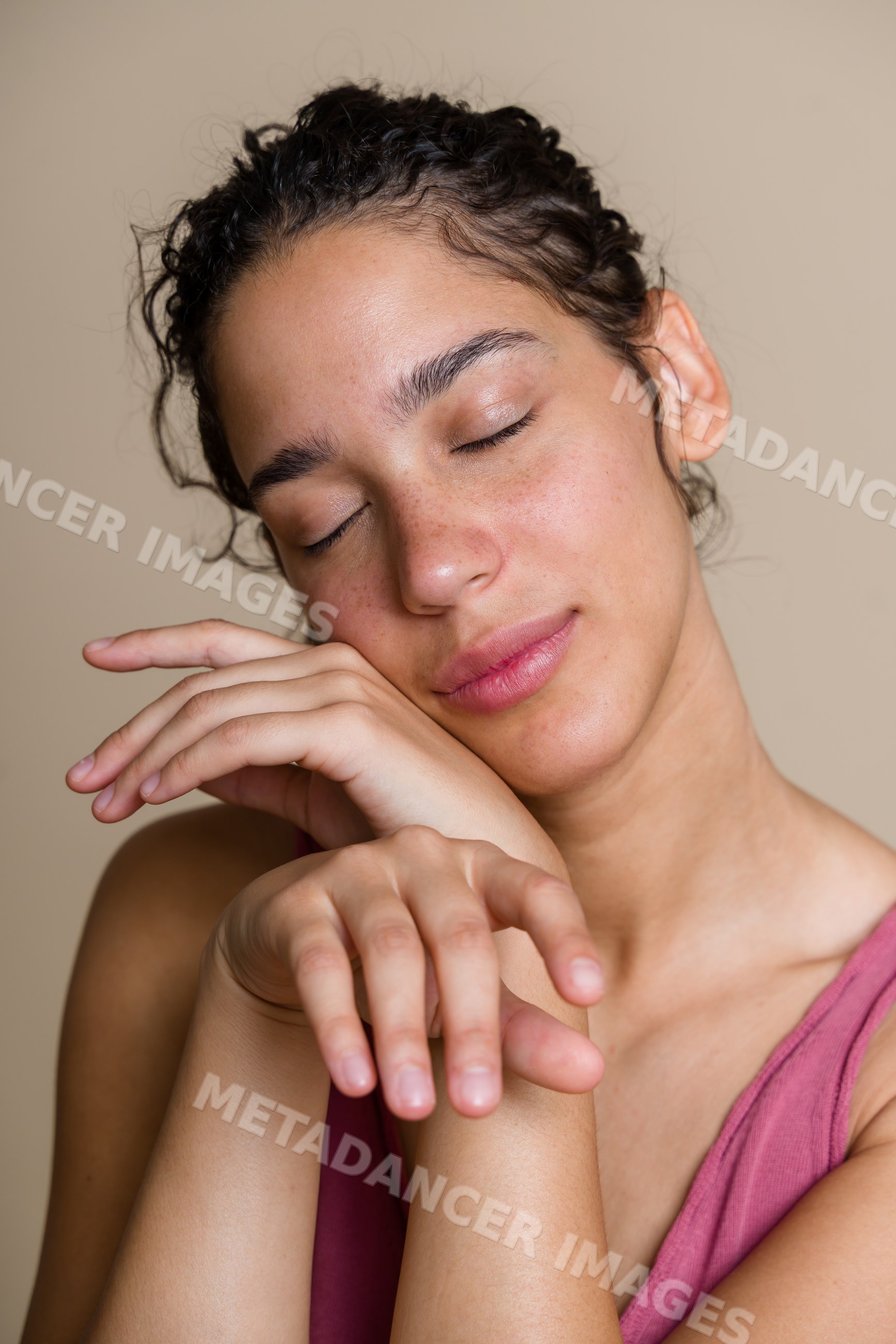 Hispanic woman with closed eyes resting face on hands in calm pose