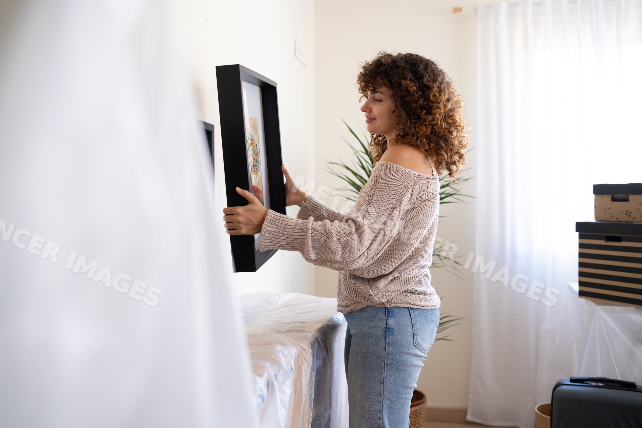 White woman hanging picture frame indoors during moving